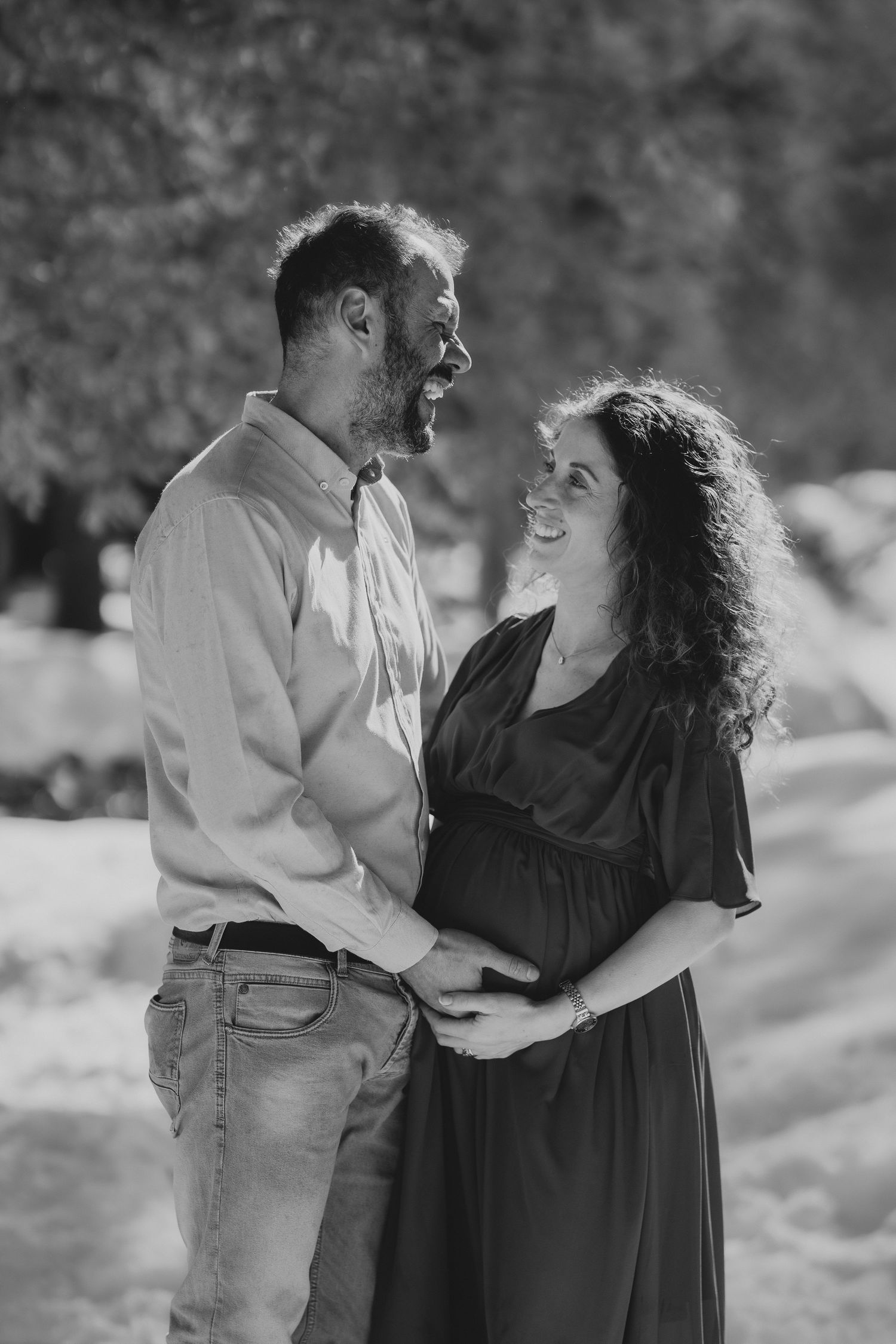 Black and white portrait of smiling couple embracing outdoors in snowy winter setting.