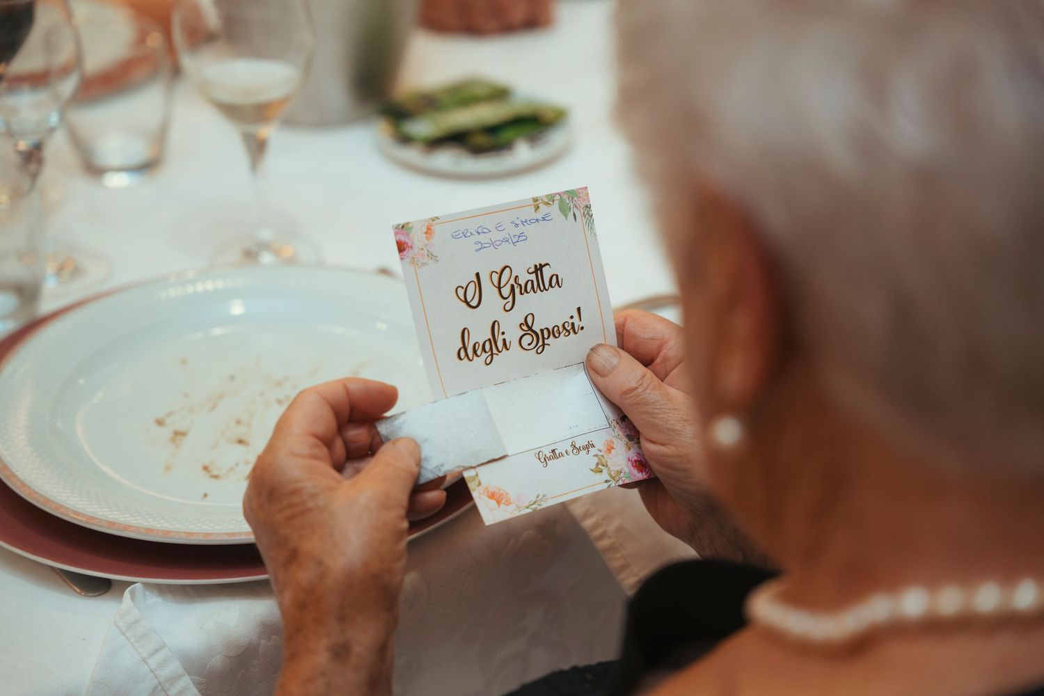 Elderly guest reading an Italian wedding menu card at a beautifully set wedding reception table.