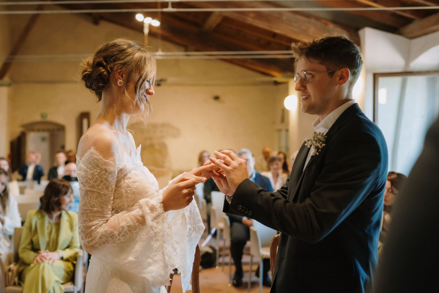 Bride and groom exchange wedding rings at the altar during their ceremony, smiling joyfully at each other.