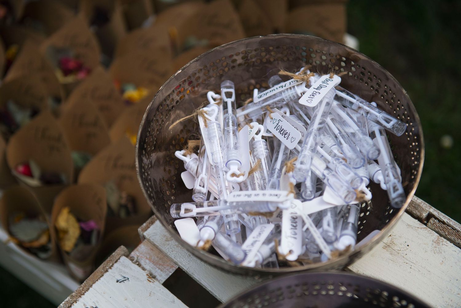 Decorative metal bowl filled with personalized wedding bubble wands for guest celebration.