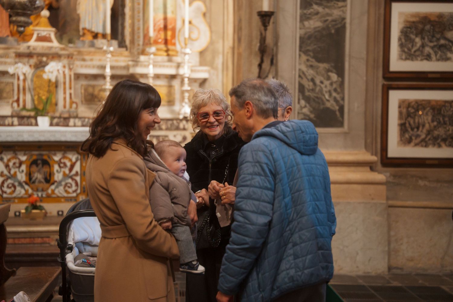 Family gathering inside a historic church with adults and a baby sharing a joyful moment.