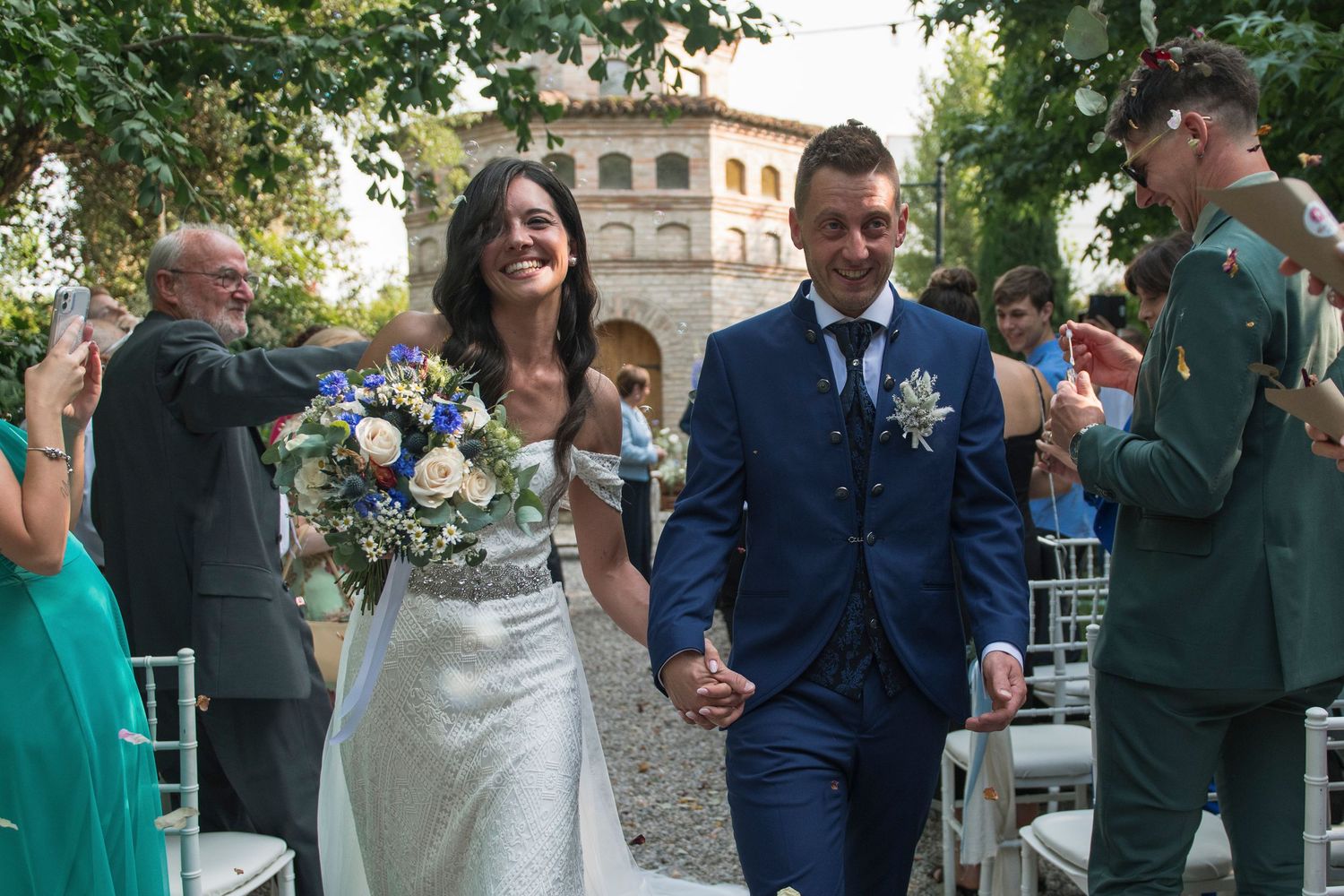 Bride and groom walk hand-in-hand after outdoor wedding ceremony at elegant villa.