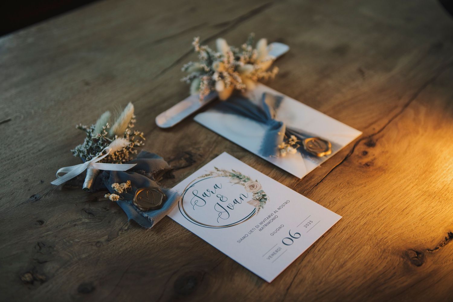 Elegant wedding invitation suite with dried floral accents displayed on rustic wooden table.
