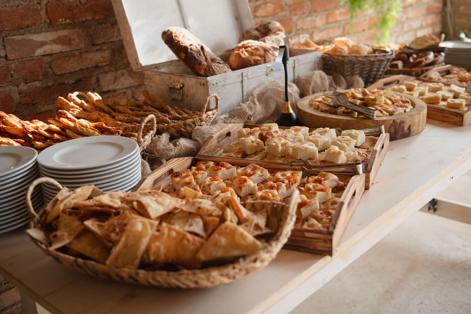 Elegant wedding buffet table with assorted breads, pastries, and baked goods in wicker baskets.
