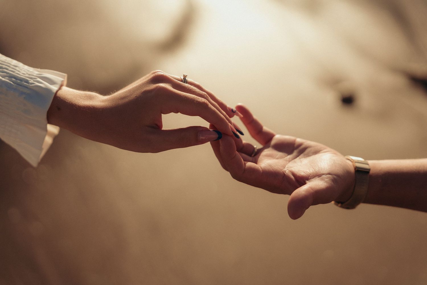 Two people gently touching fingertips in a romantic and delicate gesture.