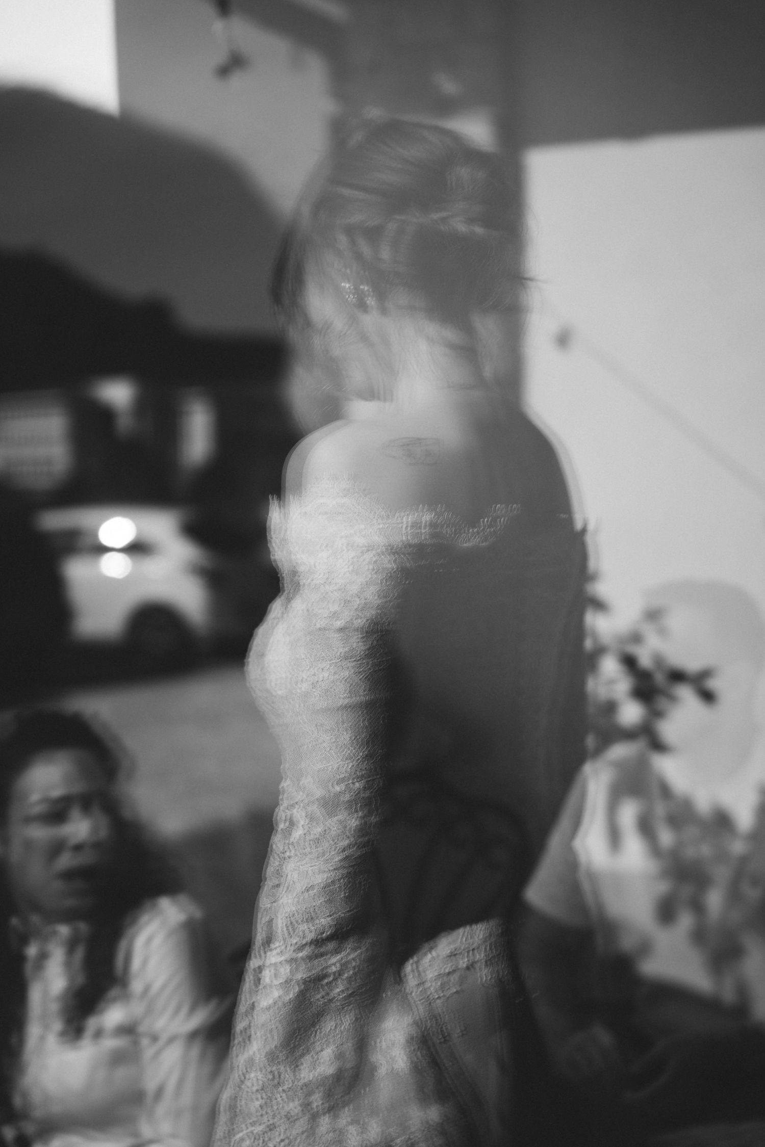 Artistic blurred black and white photo of bride in wedding dress at evening reception.
