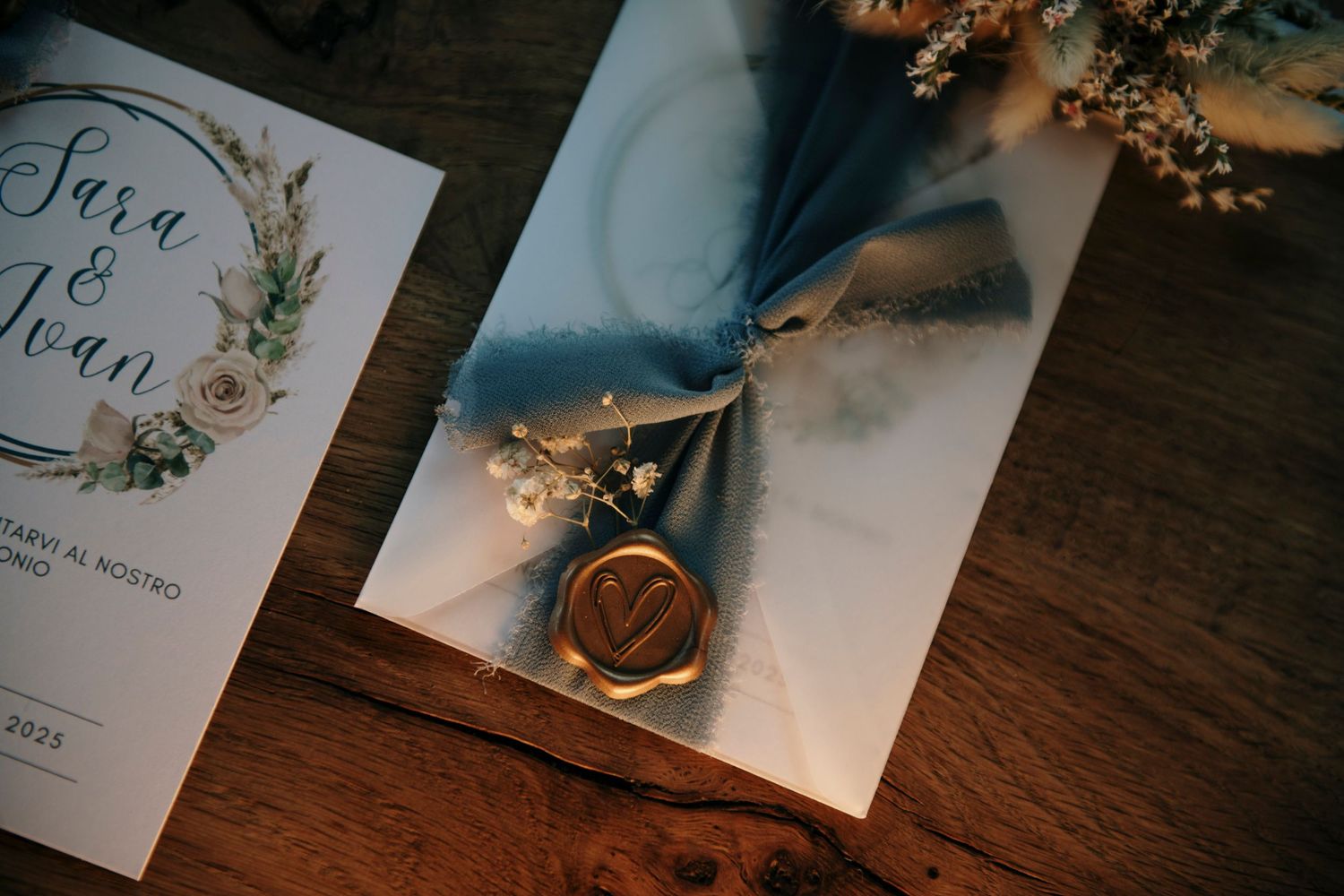 A close-up of a wax-sealed wedding invitation with floral details and the names Sara and Ivan.
