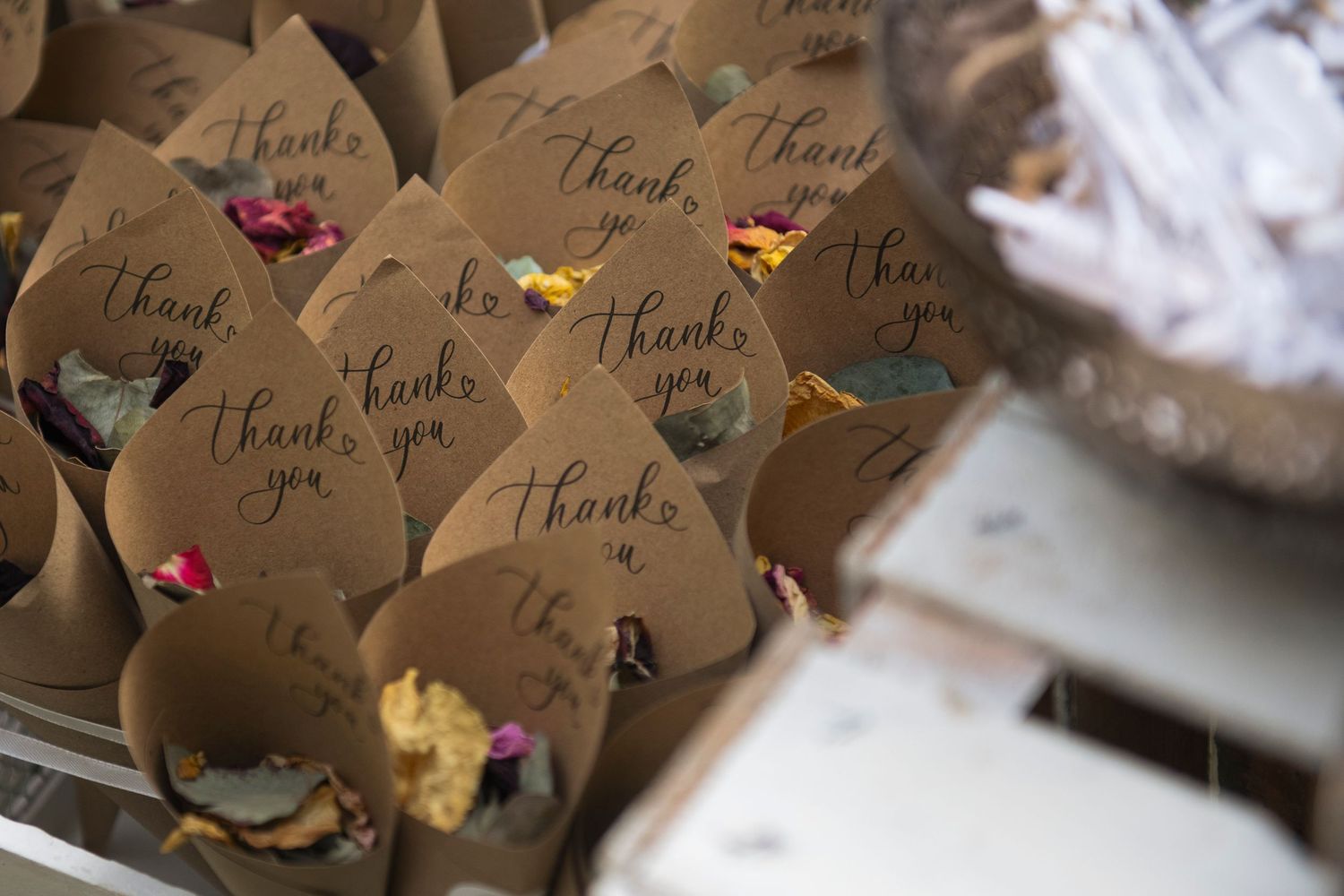 Rustic kraft paper cones filled with dried flower petals and thank you calligraphy for wedding confetti toss.