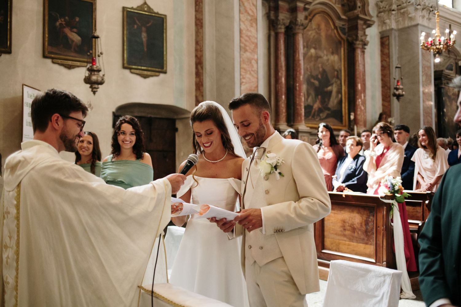 Bride and groom exchanging vows at a church altar, smiling joyfully during their wedding ceremony.