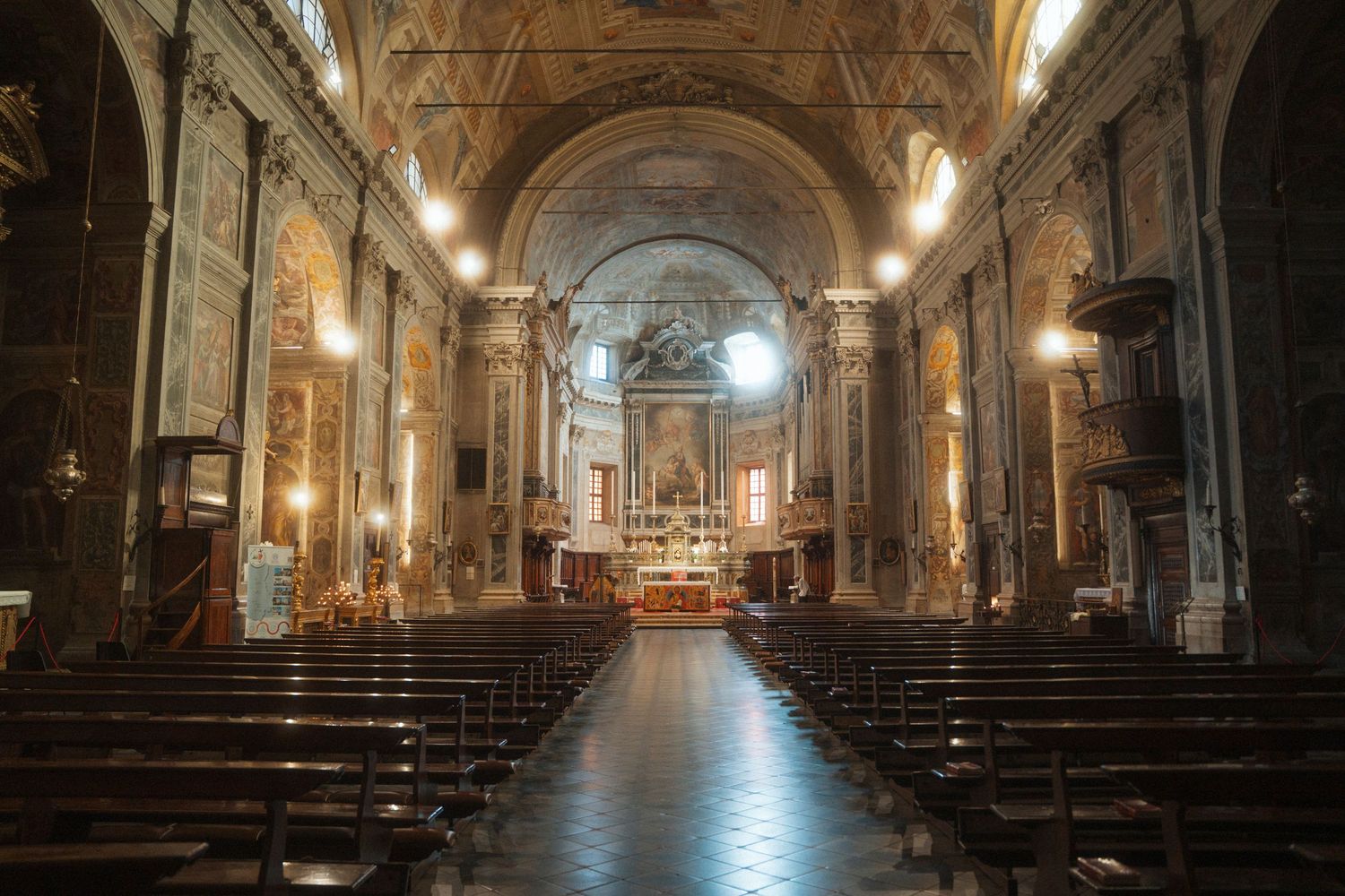 Grand ornate Catholic church interior with wooden pews and gilded altar in soft light.