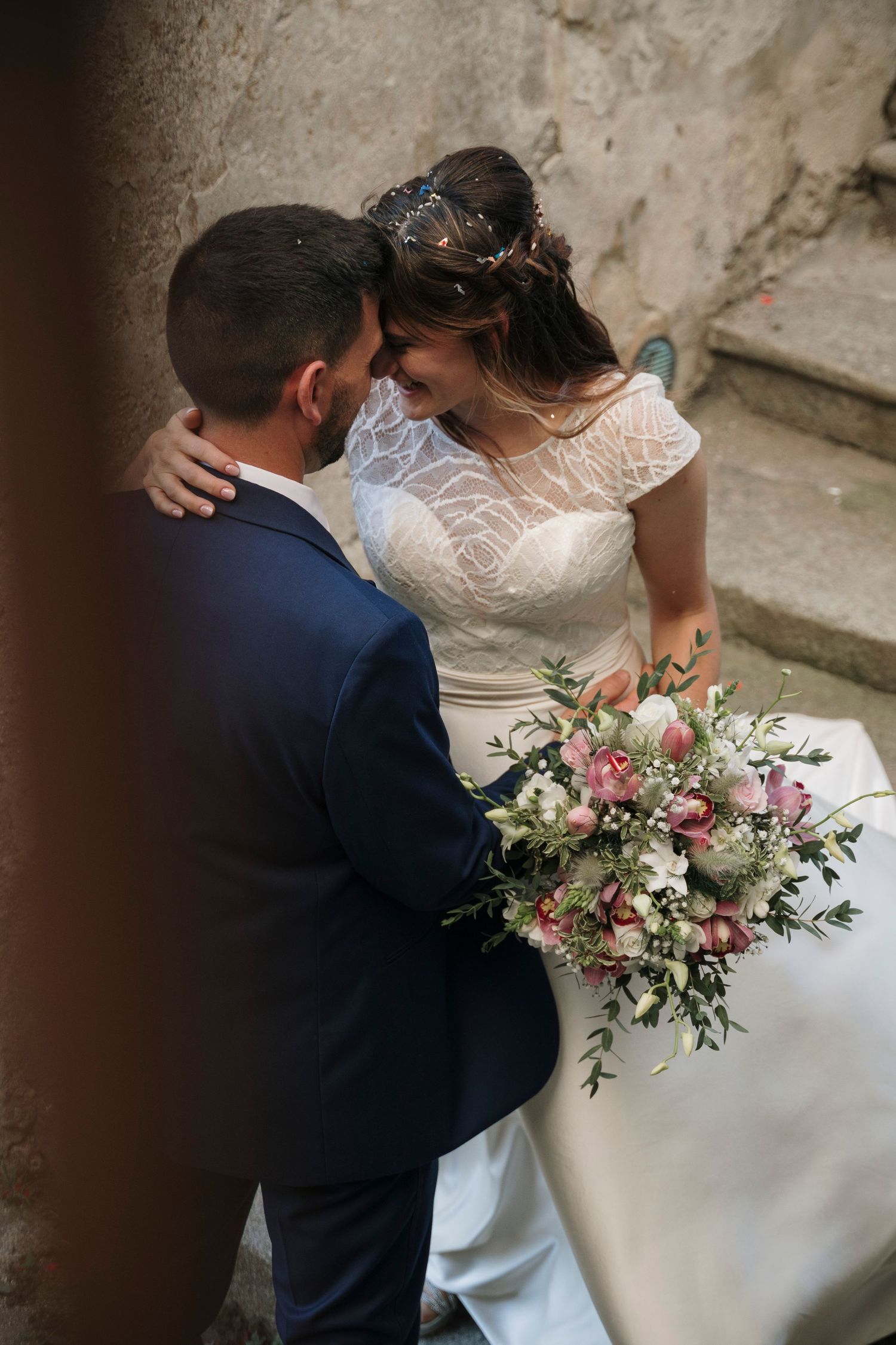 Bride and groom sharing an intimate moment with a beautiful floral bouquet on wedding day.