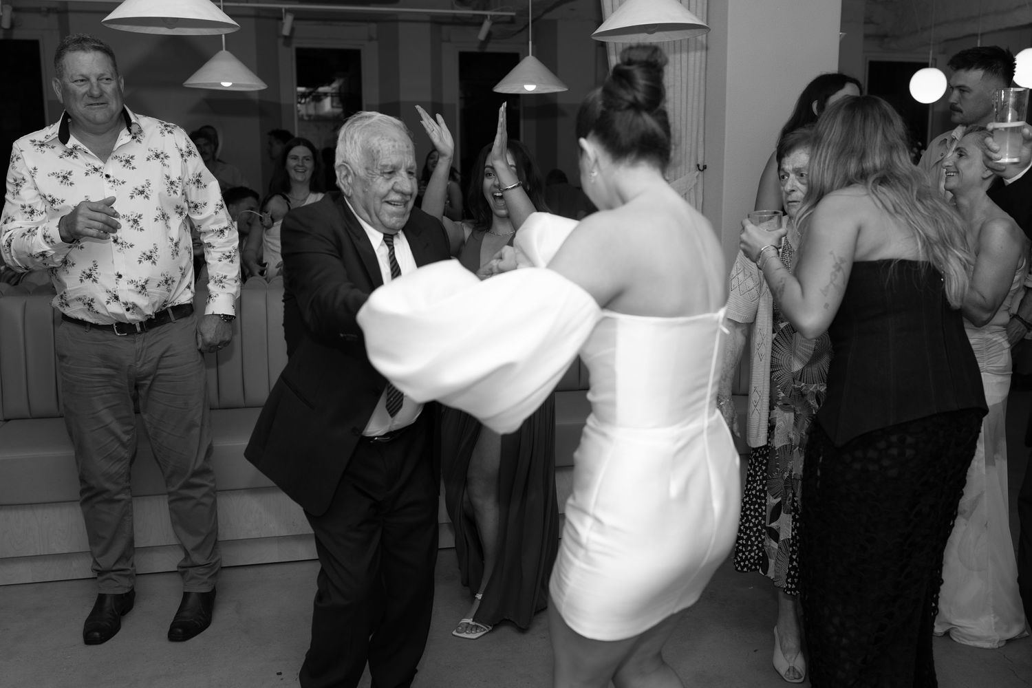 Black and white photo showing lively dancing at formal celebration.