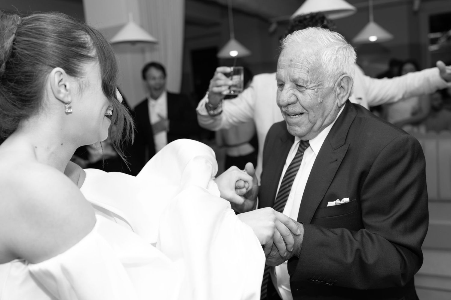 Black and white photo of older gentleman dancing with guest at formal event.