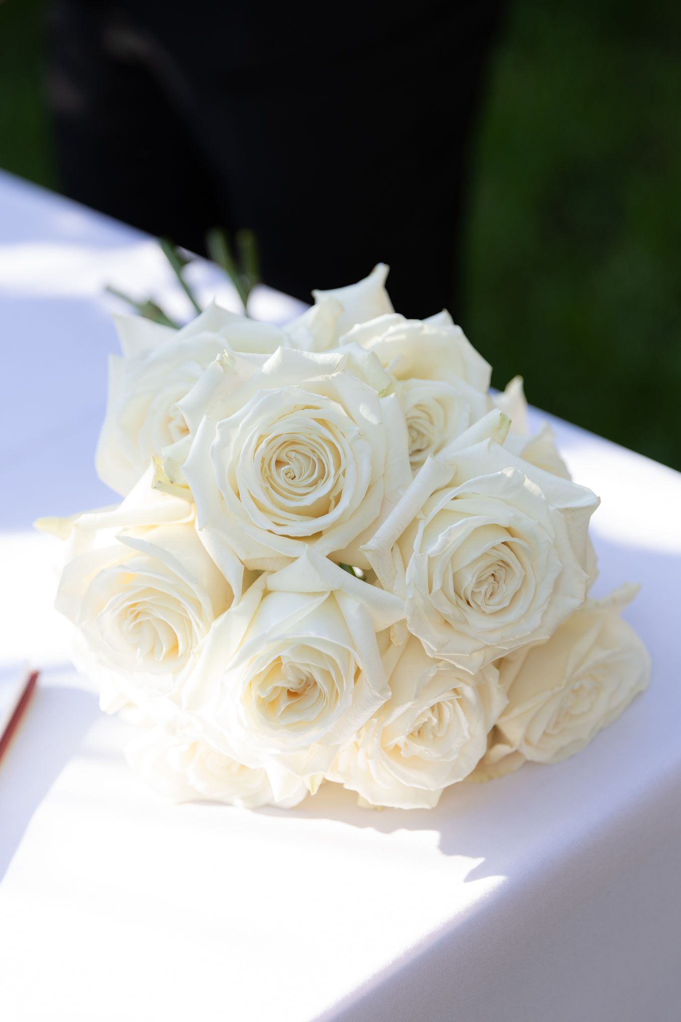 Fresh white roses arranged in a bridal bouquet on a white surface with natural lighting.