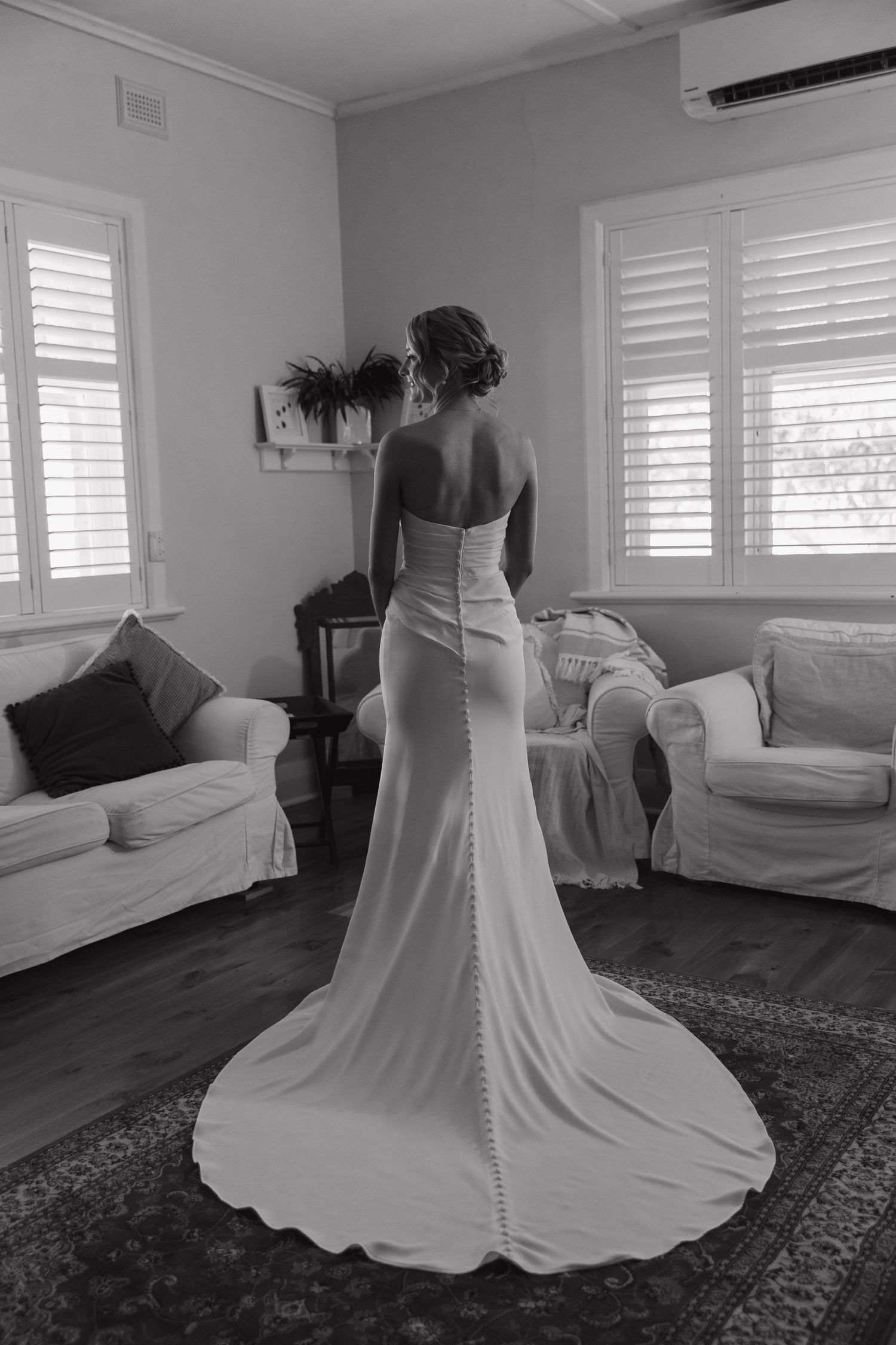Back view of a bride in a fitted wedding gown with buttons down the train.