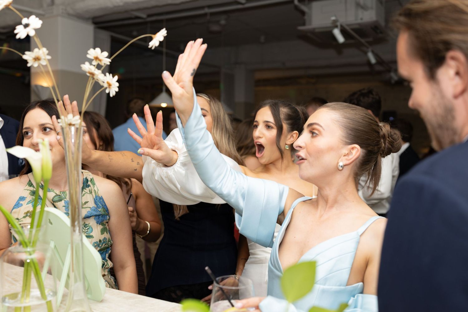 Energetic party guests cheering and raising hands during celebration.