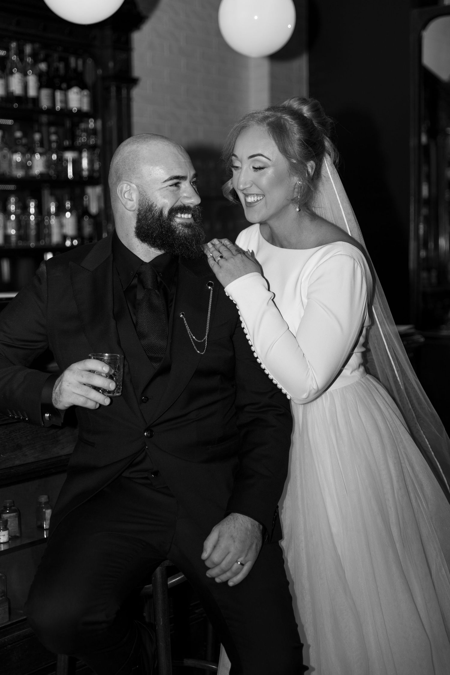 A couple sits close together at a bar sharing intimate moments in black and white photography.