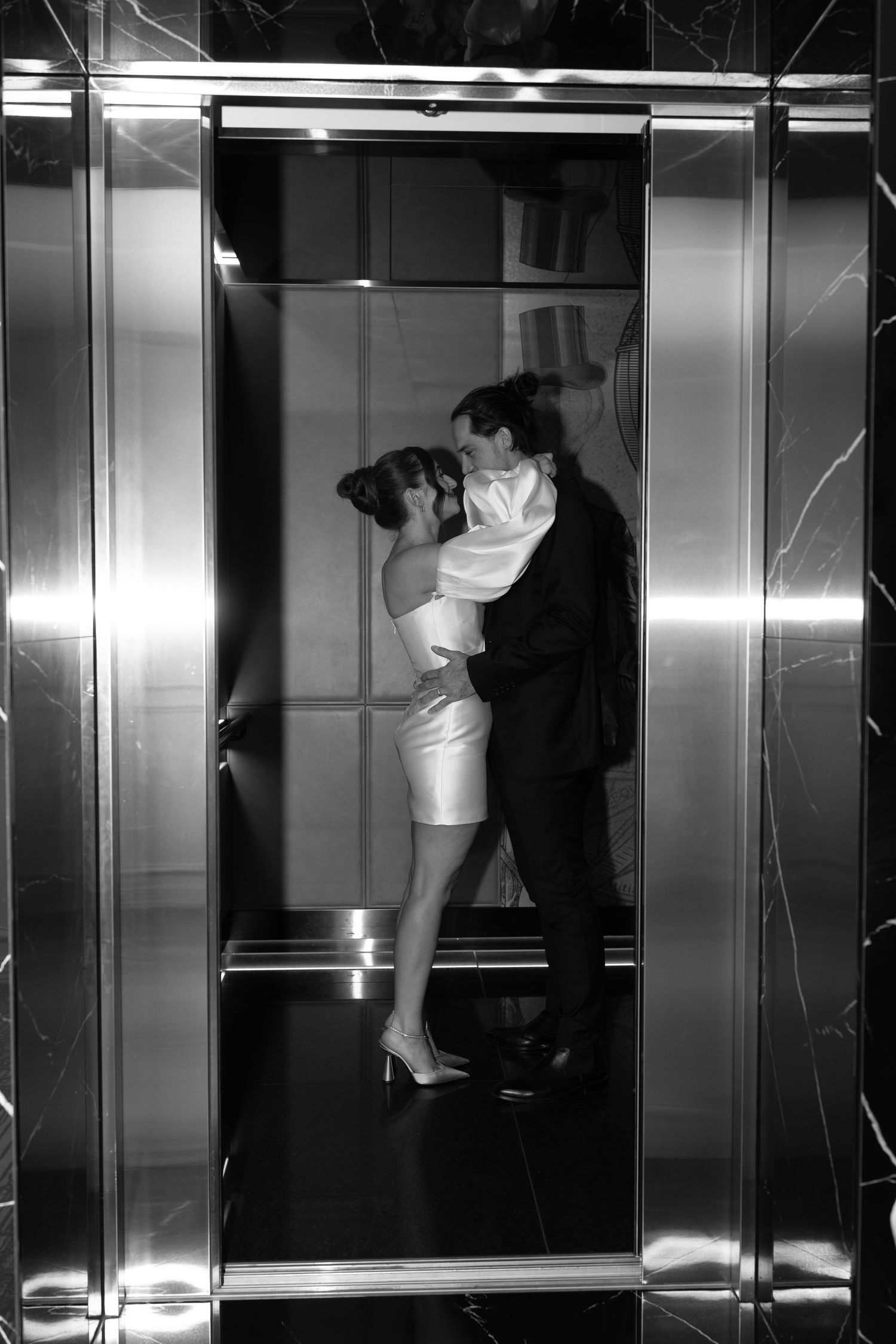 Romantic black and white photo of couple embracing in elevator.
