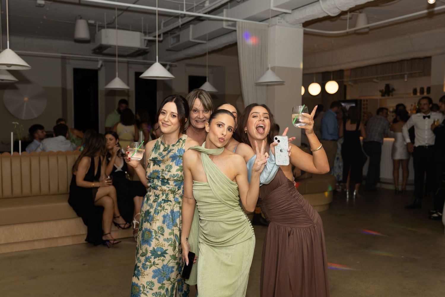 Group of friends in colorful dresses celebrating joyfully at party.