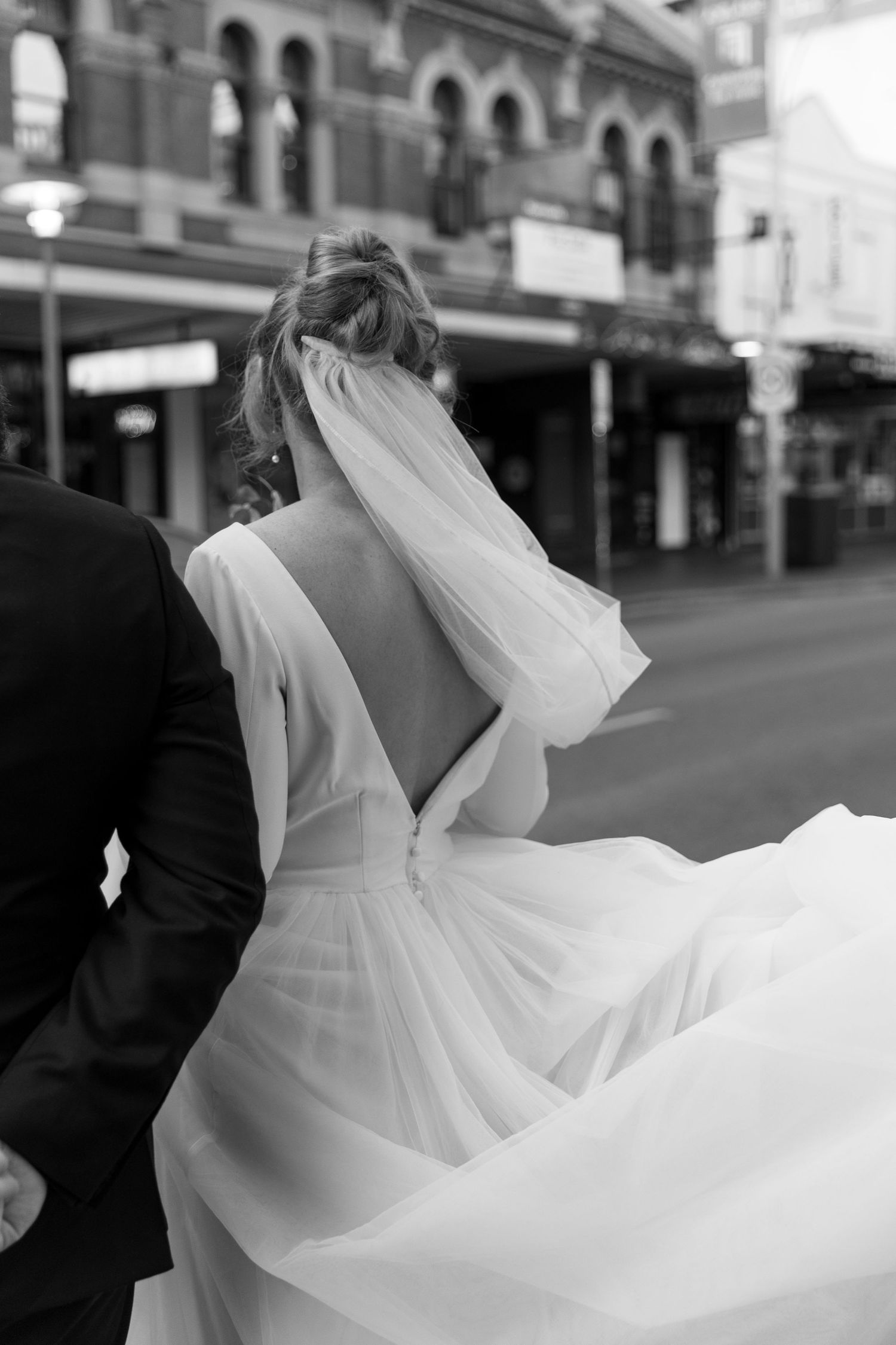Romantic black and white photo showing a flowing white dress billowing in the wind on a city street.