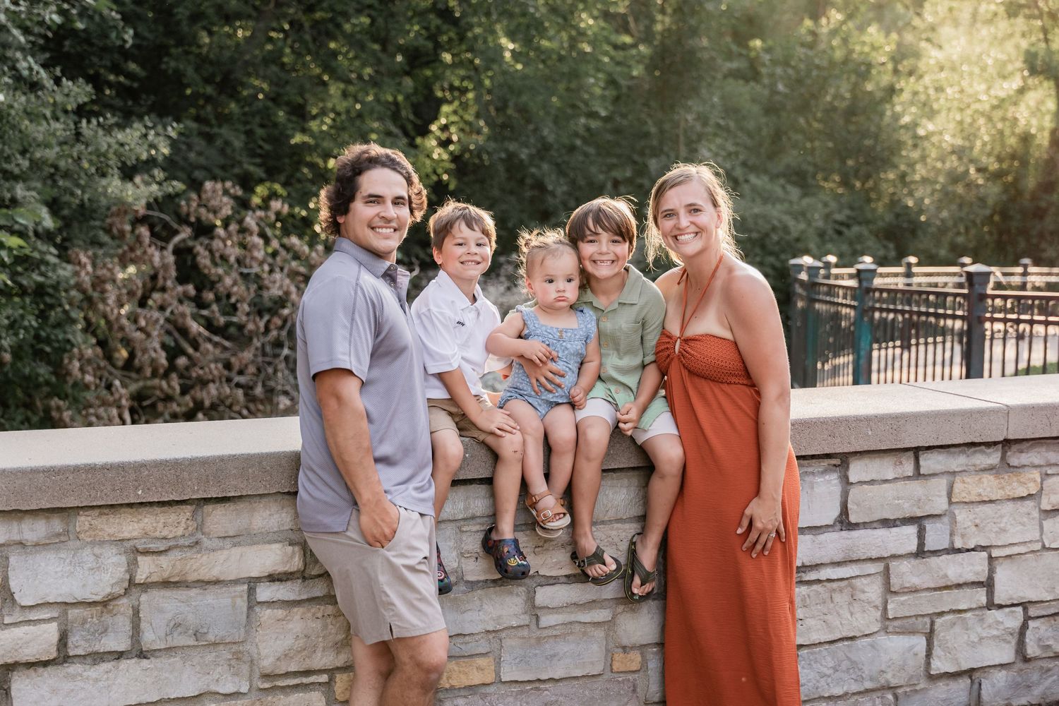 Monique and Victor surround their three children on a stone bridge overlooking Minnehaha Falls
