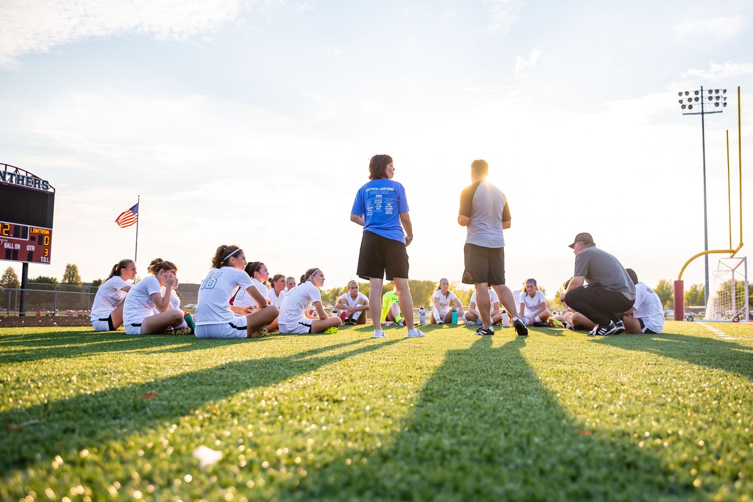 eastview high school girls soccer varsity team huddle as sun sets