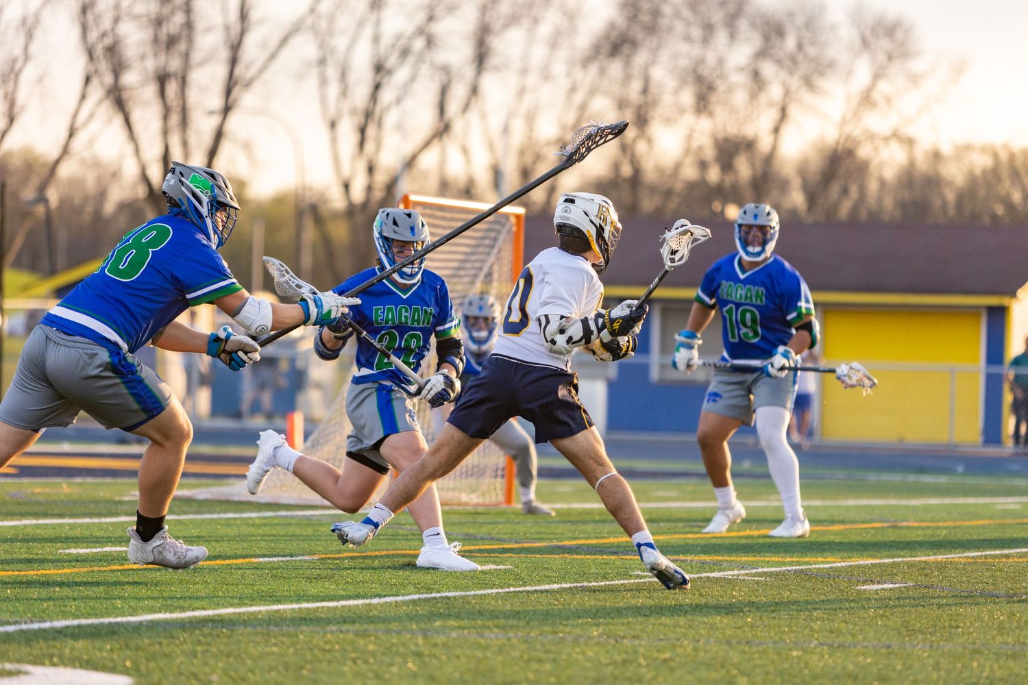 Rosemount Irish lacrosse player dodges around a set of defenders to make a pass to a teammate