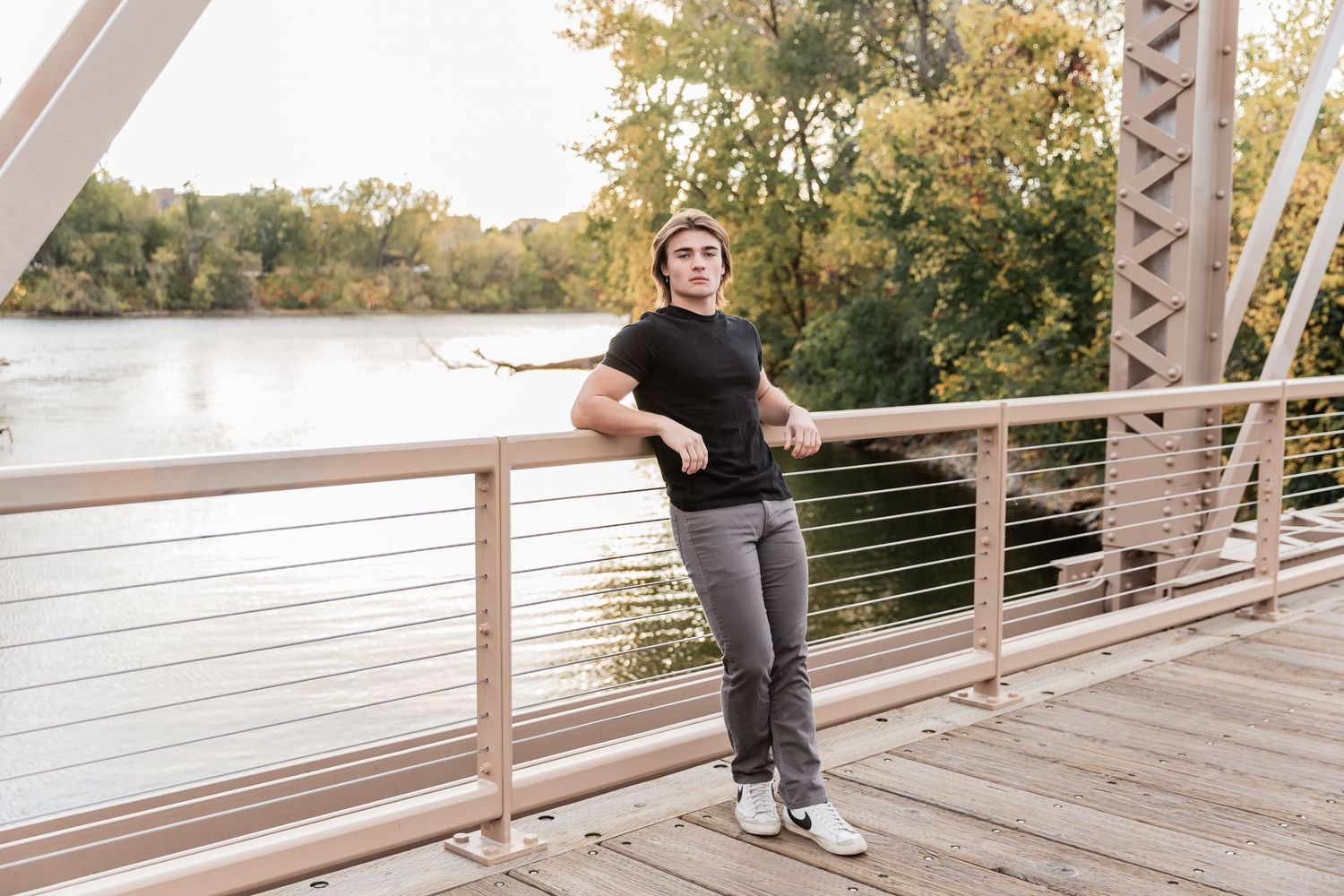 Lakeville South senior football player rests against the railing of a footbridge over the Mississippi River at Boom Island park