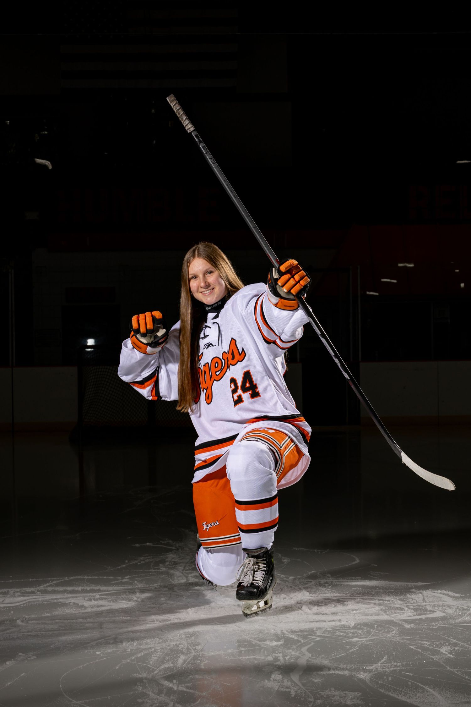 Farmington Tigers girls hockey player pretends she's shooting a bow and arrow for her media day pose