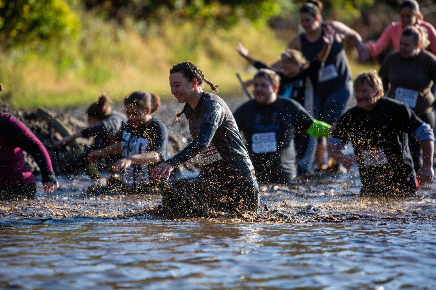 People try to run through a deep pool of muddy water for the Terrain Race