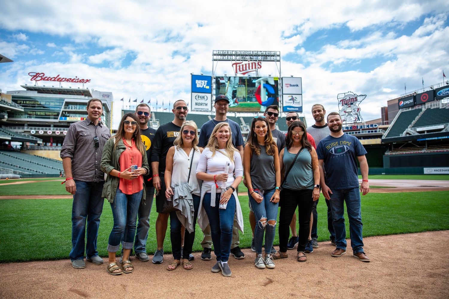 Large group of friends stand on the warning track for Target Field on a warm sunny day for a craft beer festival