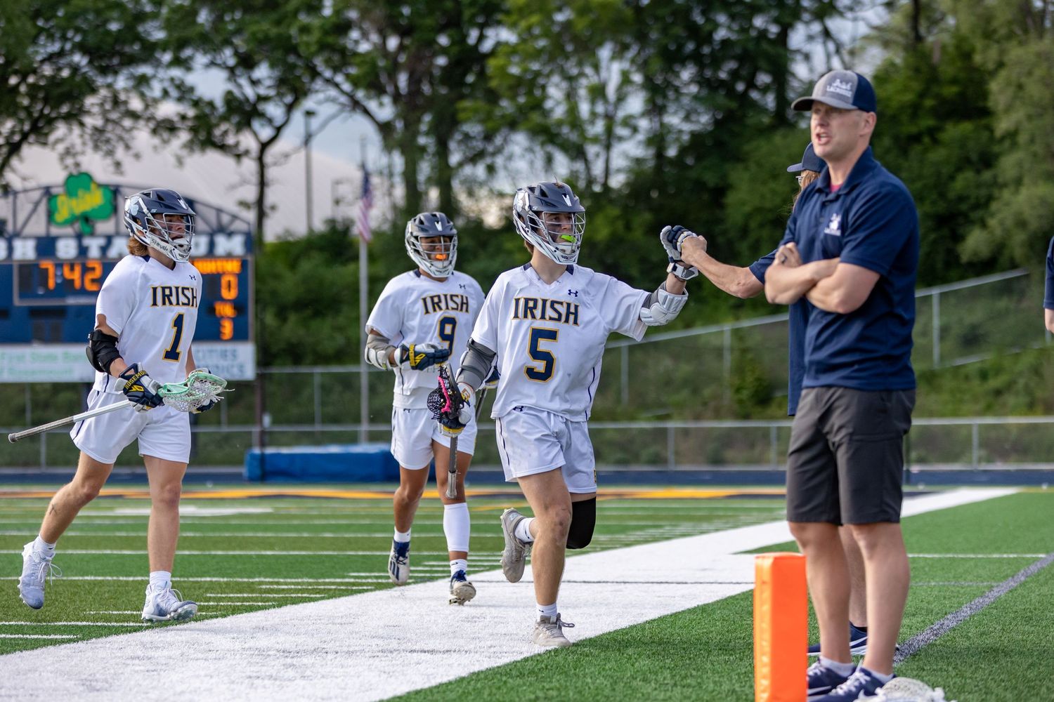 Rosemount Irish lacrosse players high five their coach after scoring