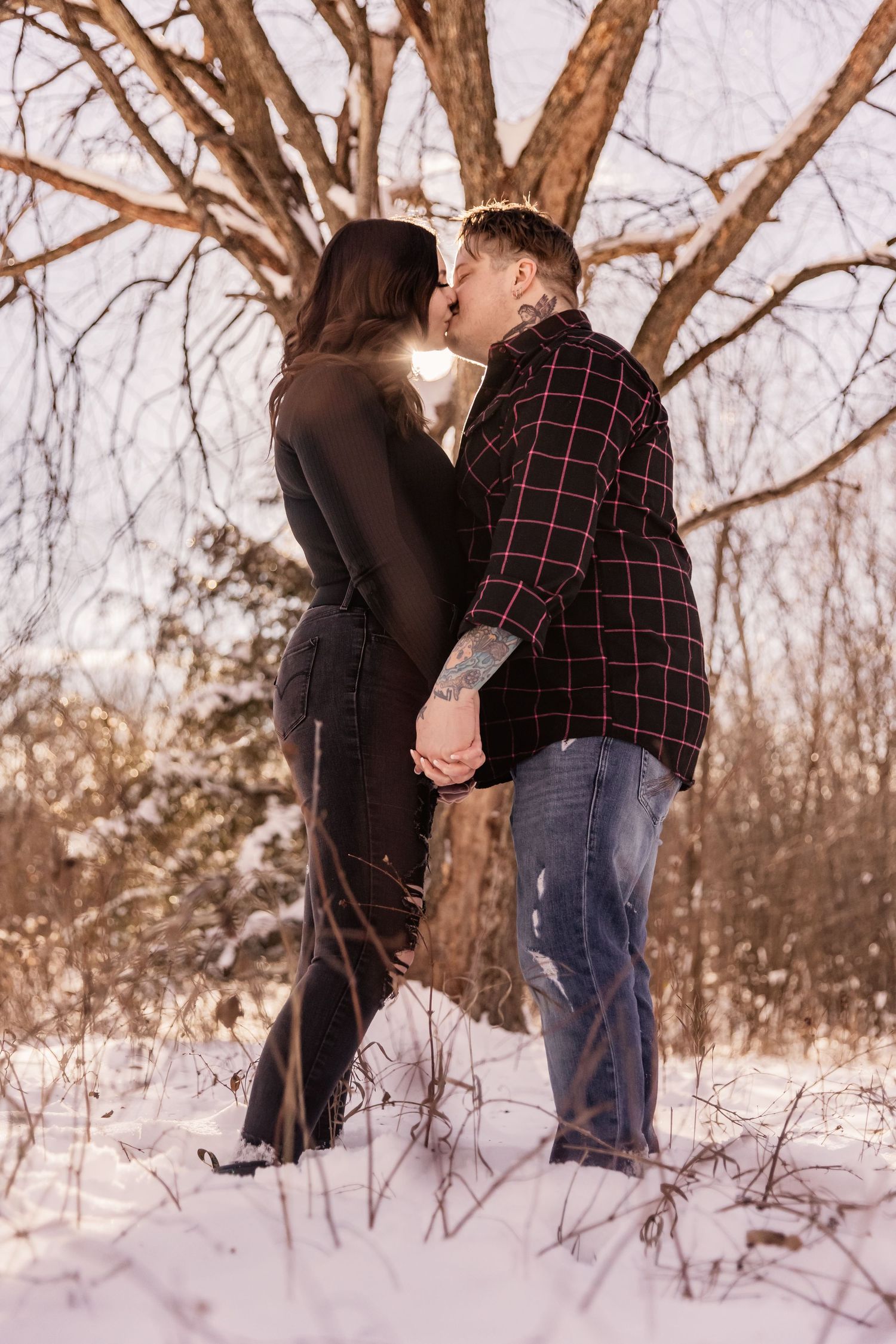 engaged couple embraces in a loving kiss in the snowy woods