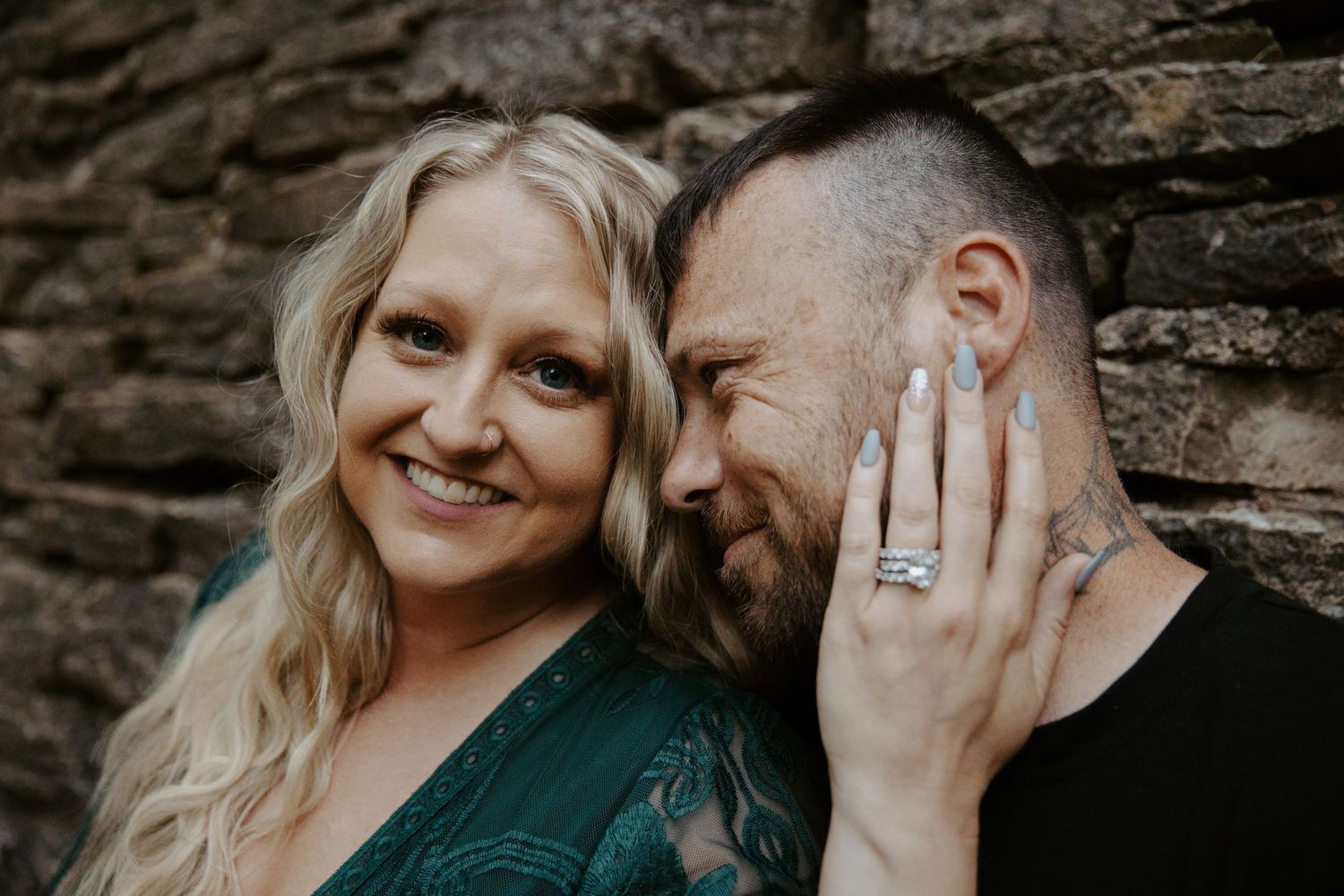 Woman rests her hand on her fiances face to show off her massive diamond ring