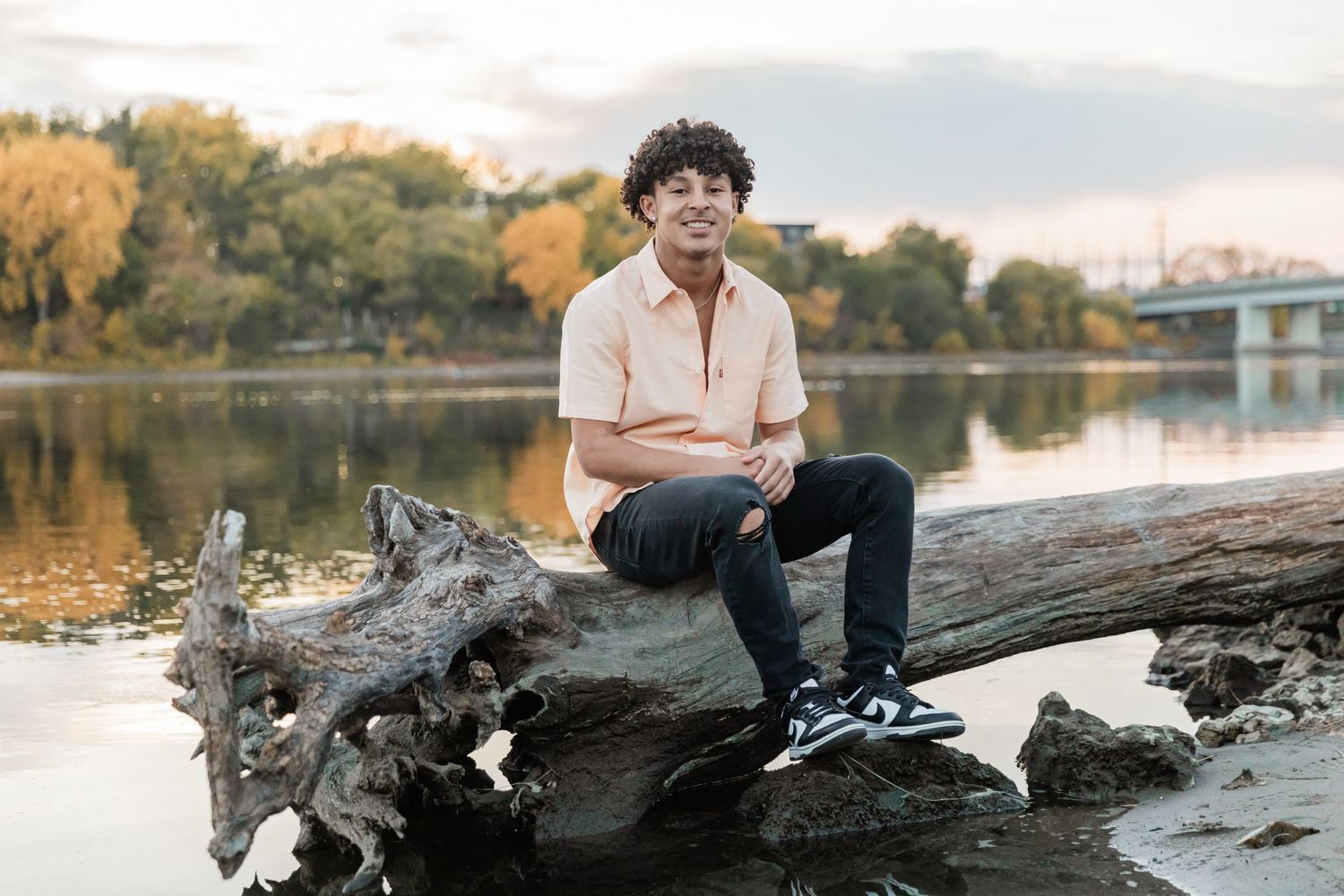 Jestin sits on a large dead tree in the Mississippi River alongside Boom island Park
