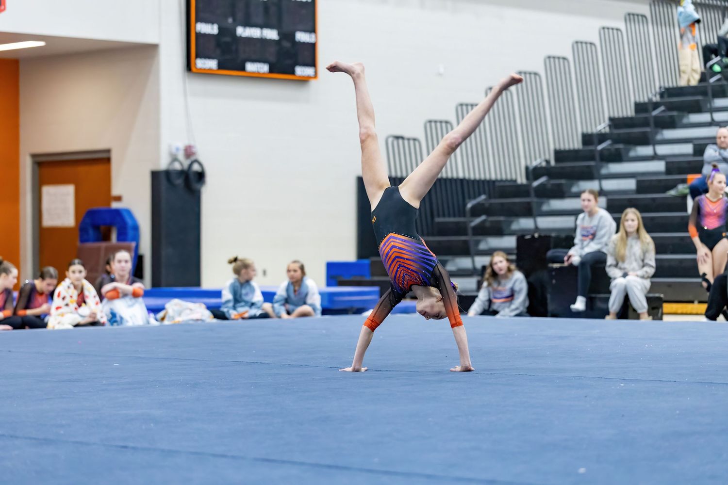 Youth gymnast does a cartwheel as she launches into a backflip for her floor routine