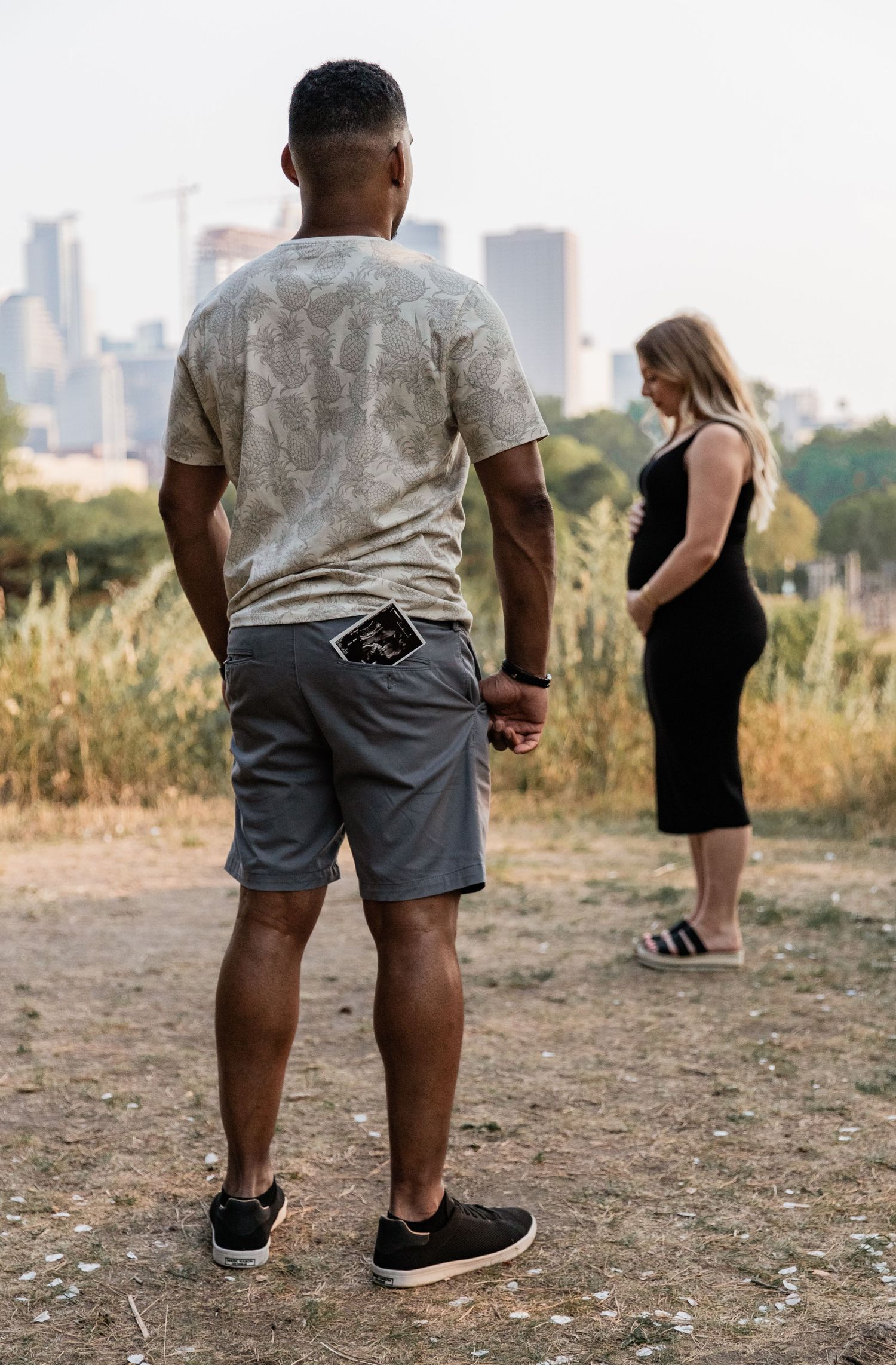 Husband stands adoring his pregnant wife with an ultrasound print out hanging out of his pocket