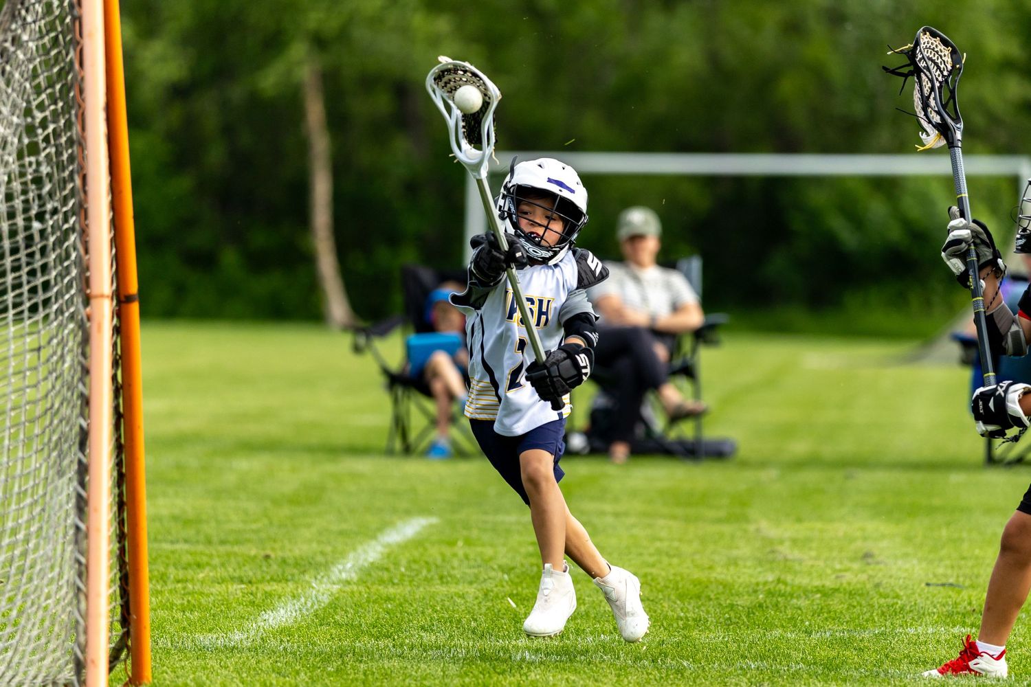 Youth lacrosse player takes a shot on goal from the outside angle