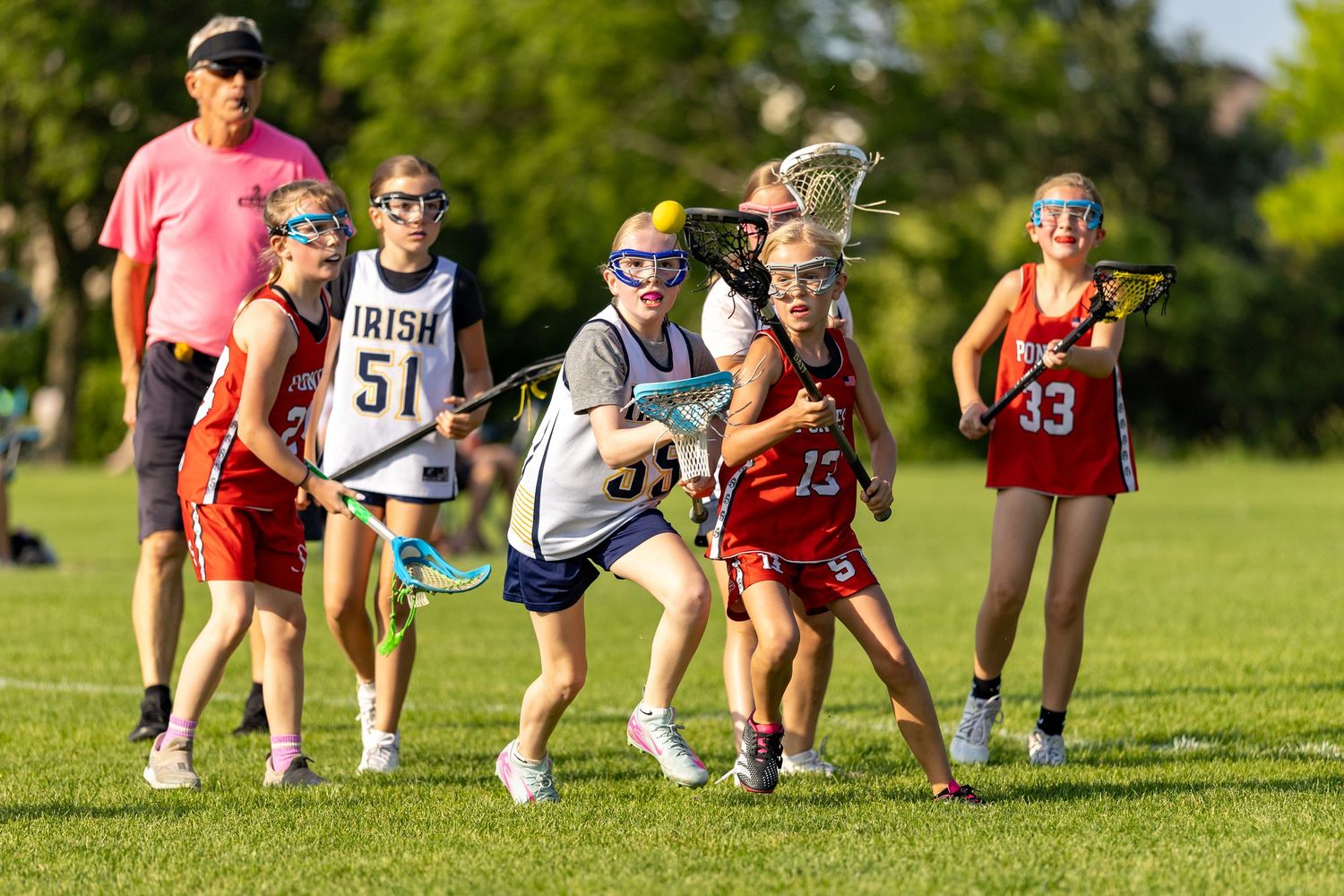 Girls youth lacrosse player focused on the ball as she fights off a defender