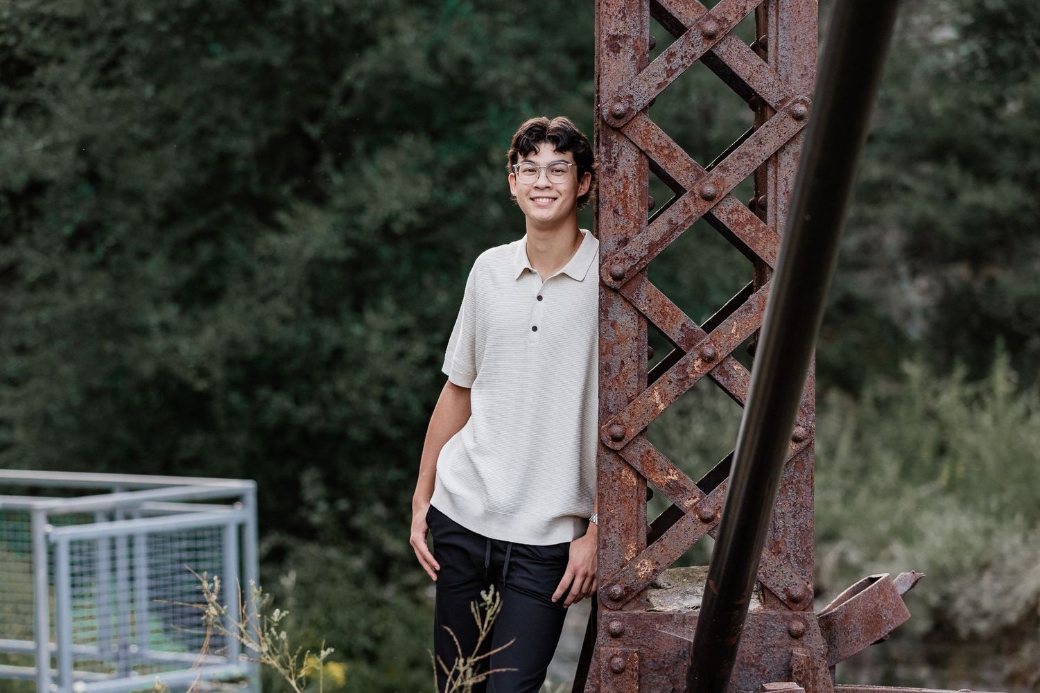 David leans against a rusted over steel beam at Mill Ruins Park in Minneapolis for his senior photos