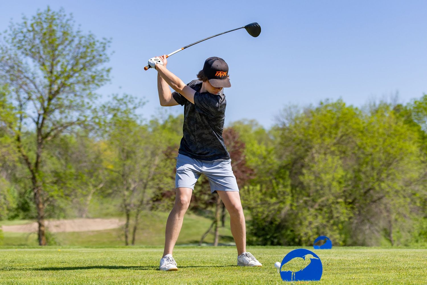 Farmington Tigers boys golf player mid swing as he tees off