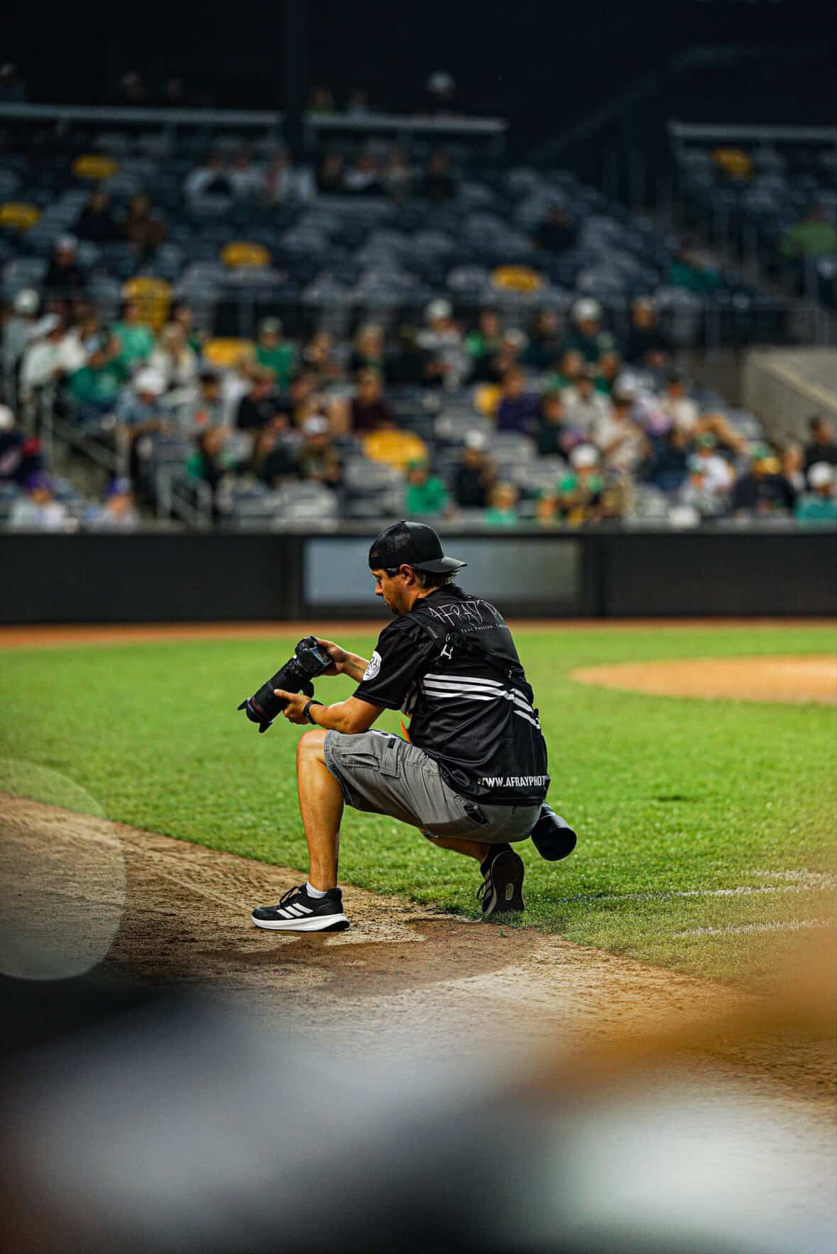 AFRAY Photo crouches on the warning track to check a photo