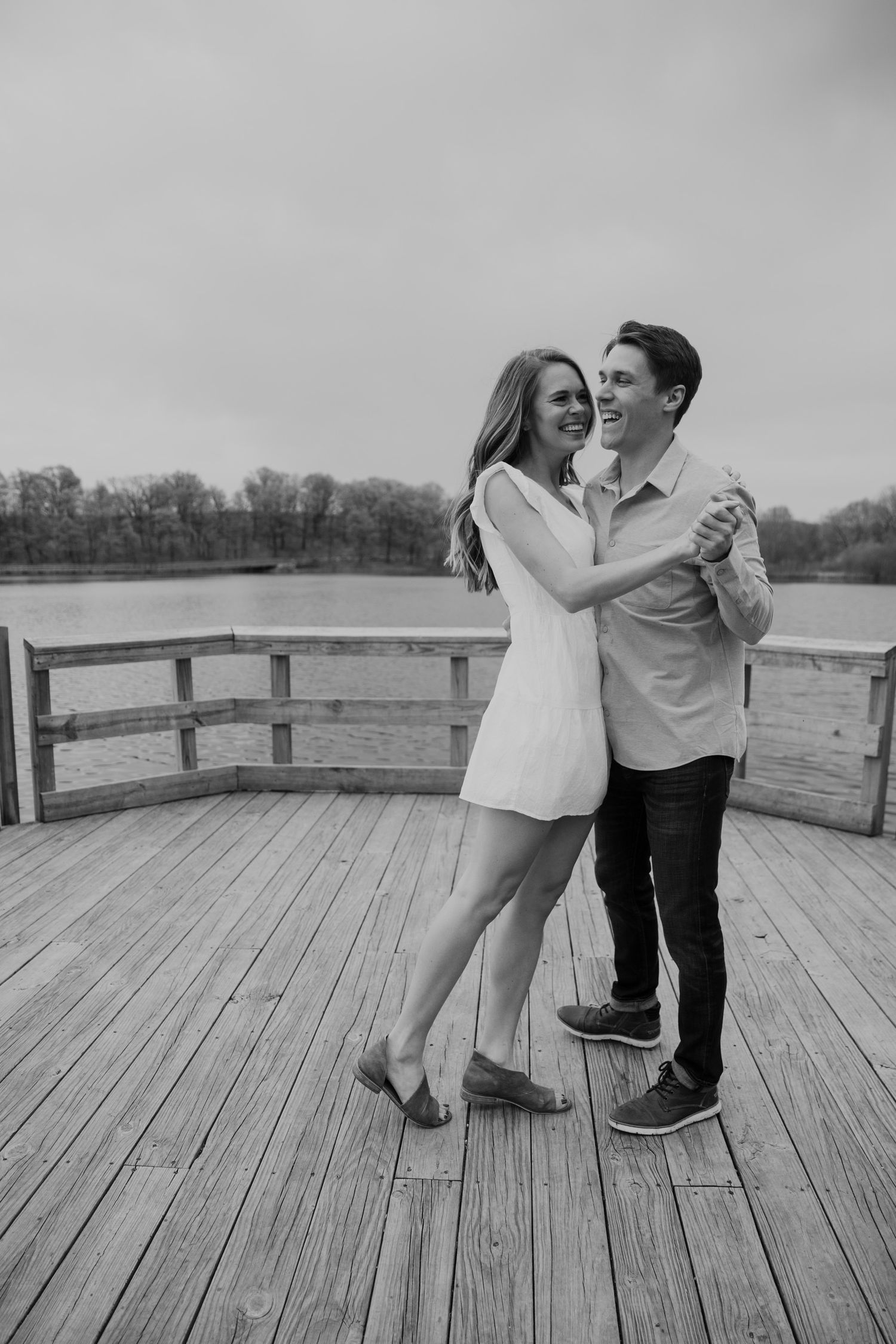 Young couple dances on a wooden dock to celebrate their engagement