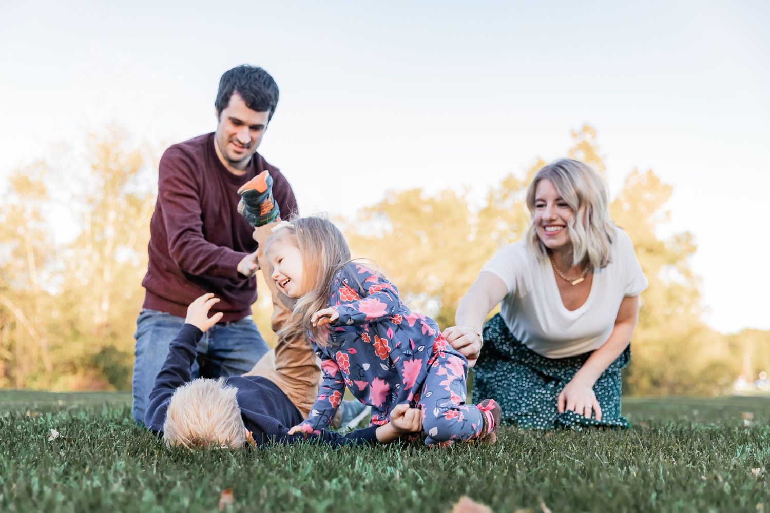young family wrestles in the grass during tickle fight riley lake park mn eden prairie