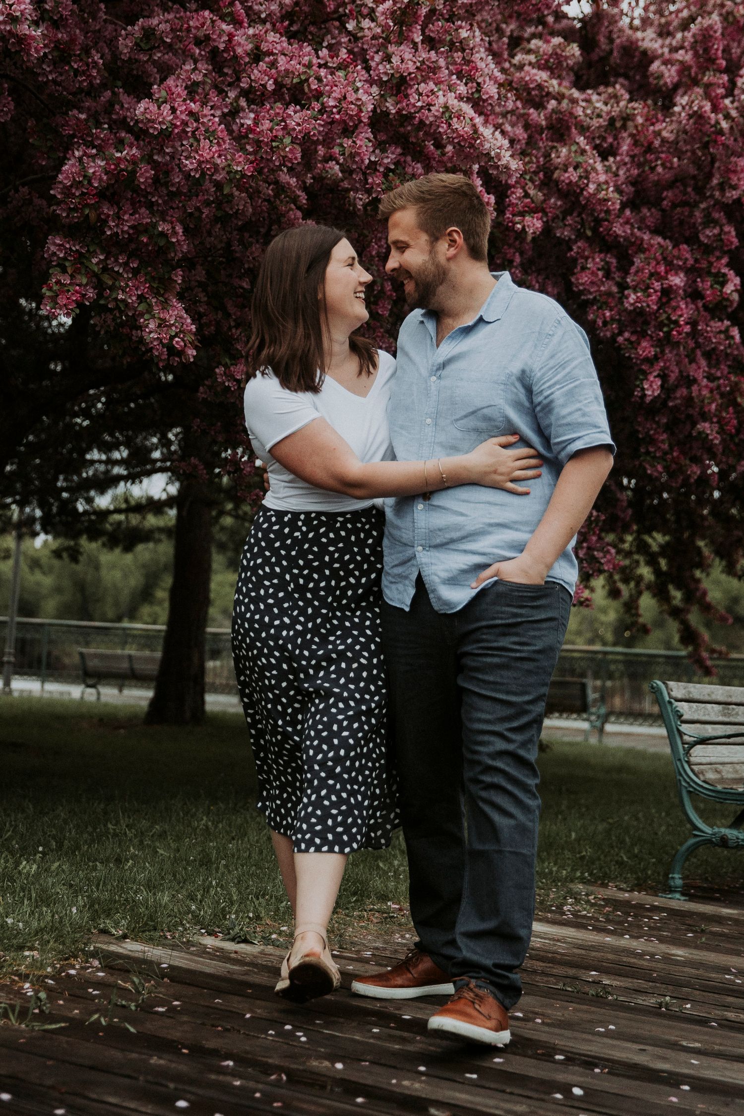 engaged couple strolls in front of a blooming tree