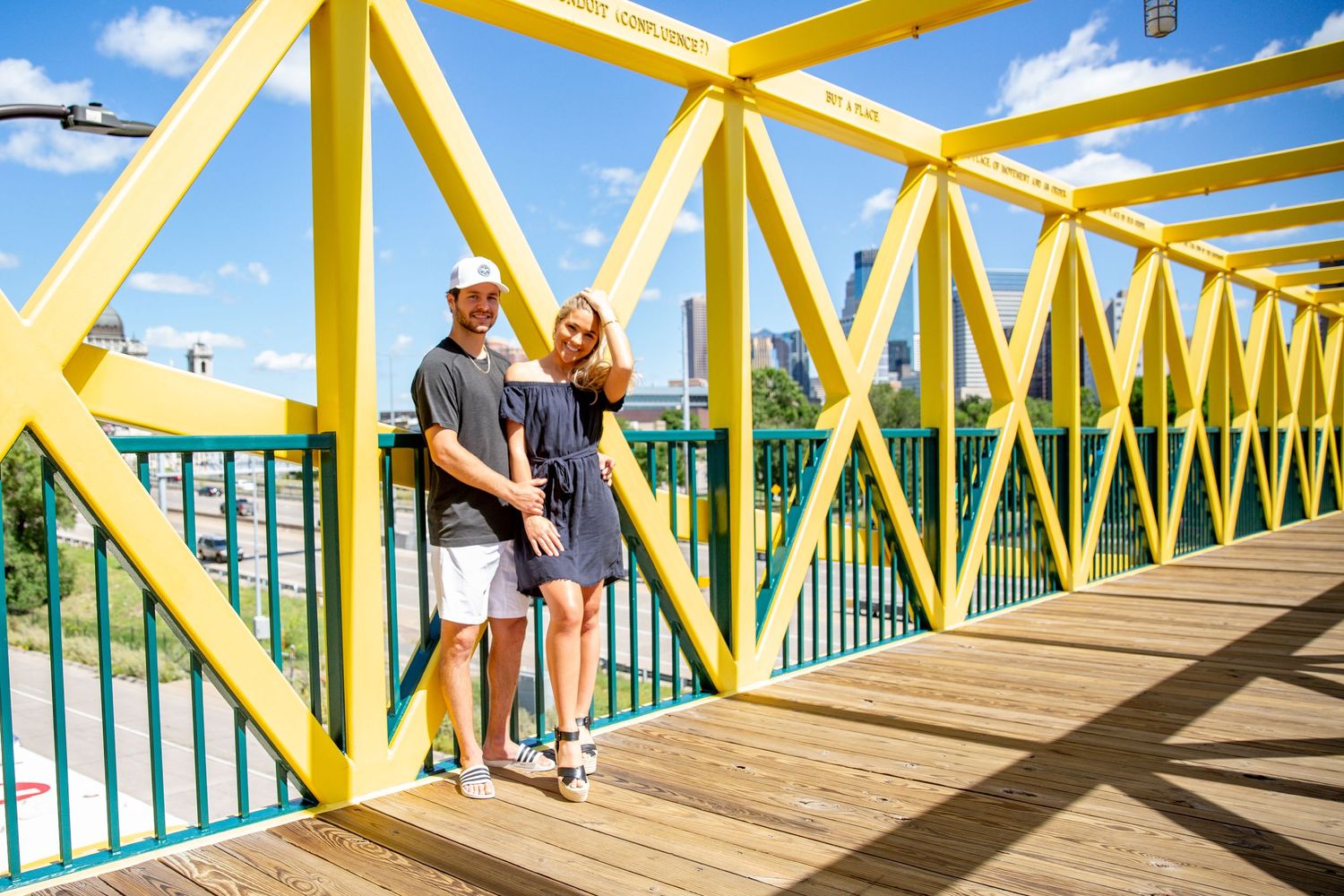 beautiful young couple stands on a bridge overlooking Minneapolis
