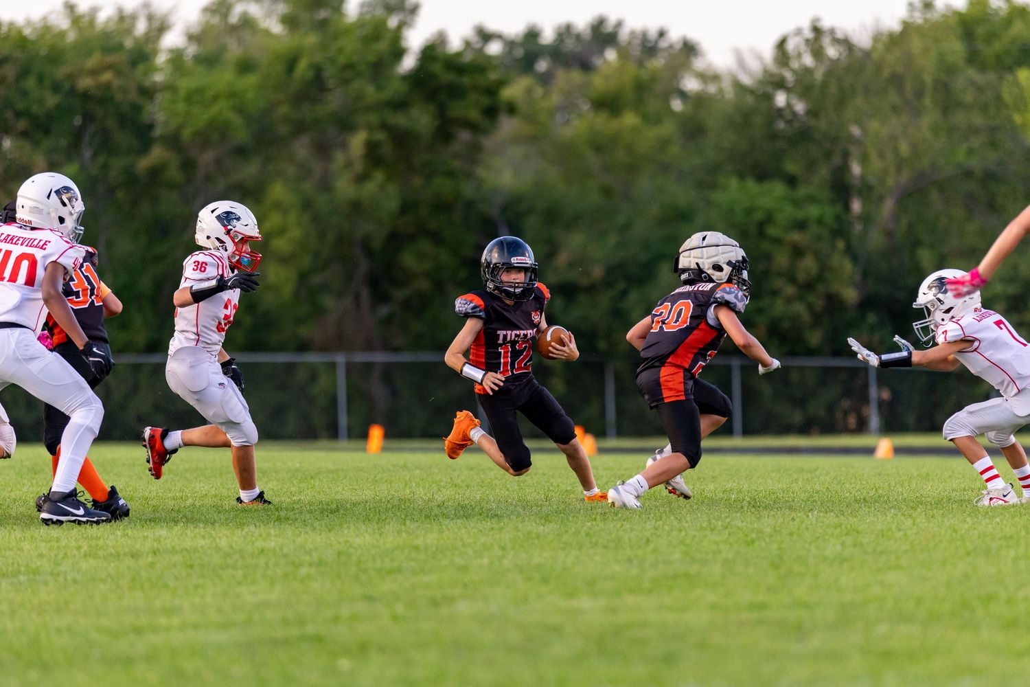 Youth football quarterback cuts back towards the middle of the field on his run to avoid the tackle