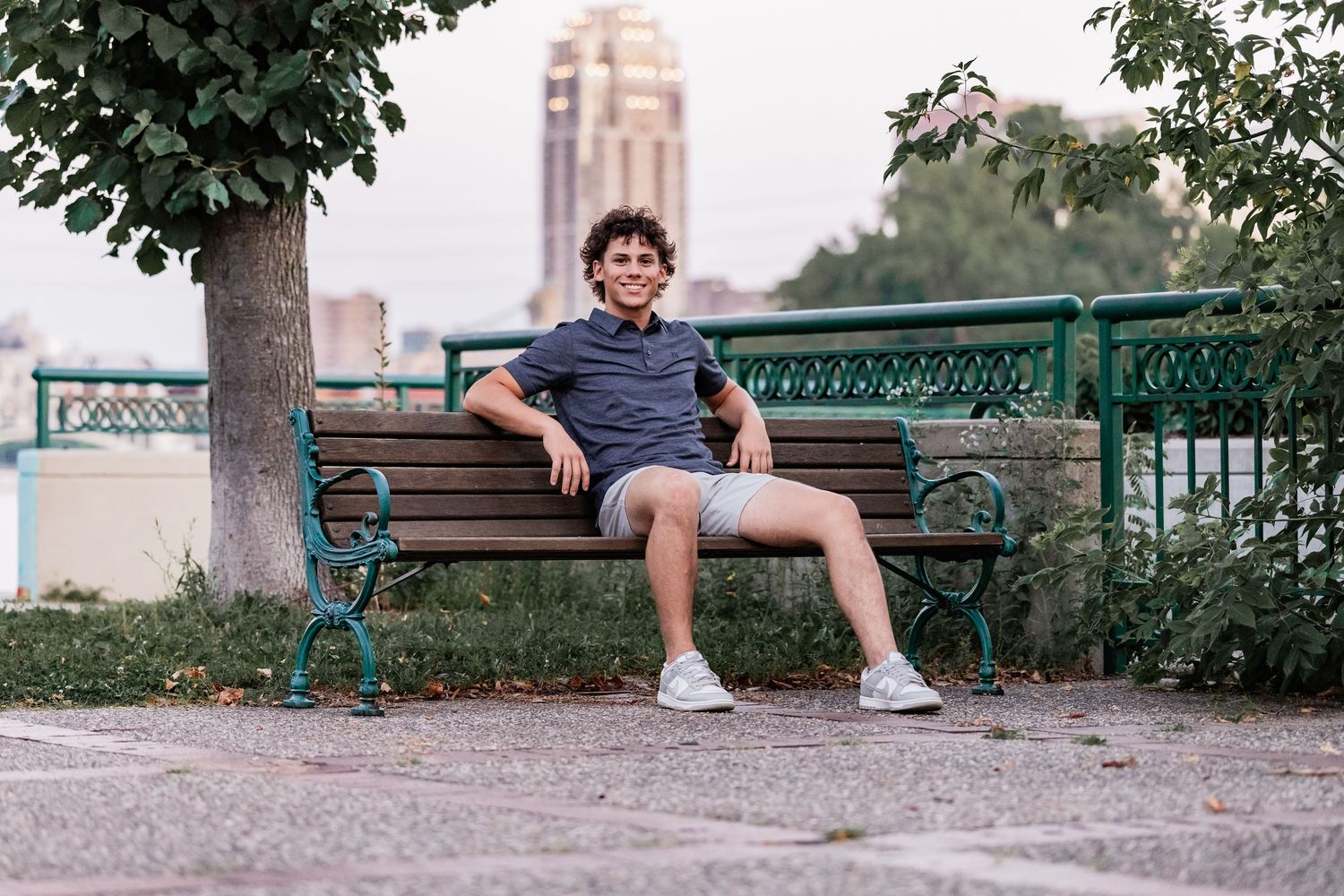 Dominic Staves sits on a wooden bench casually leaning back with his elbows resting beside him