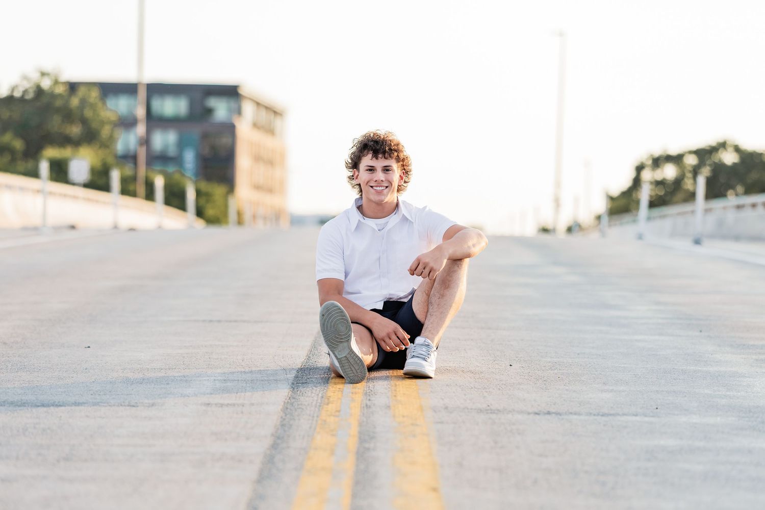 Dominic sits with one leg bent up in the middle of Plymouth Avenue bridge in Minneapolis