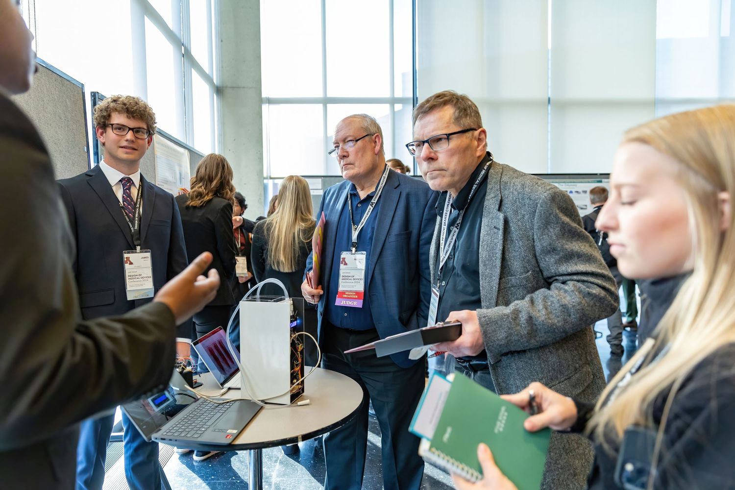 Expert judges ask questions to students presenting their medical device creations